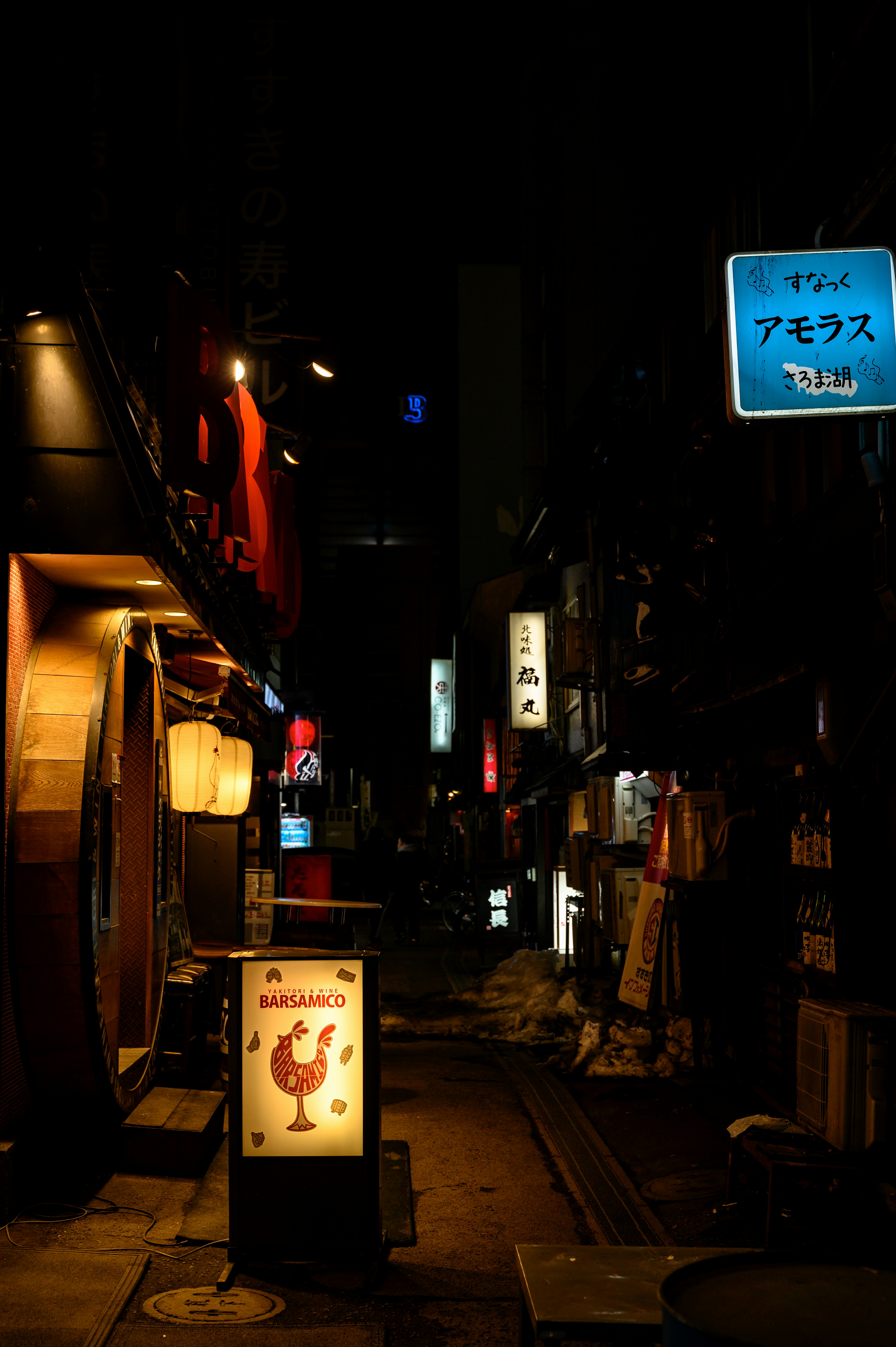 Allée étroite illuminée par des lampadaires avec un panneau de poulet