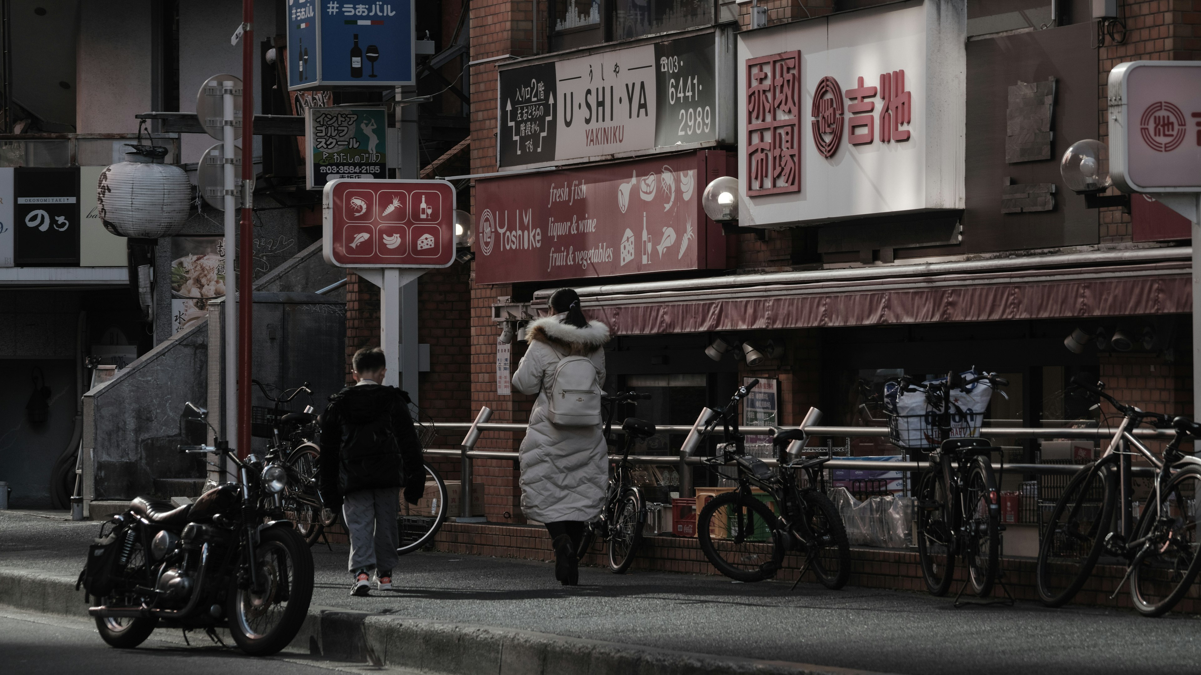 Escena de personas caminando en la ciudad con bicicletas y una motocicleta al fondo con letreros japoneses