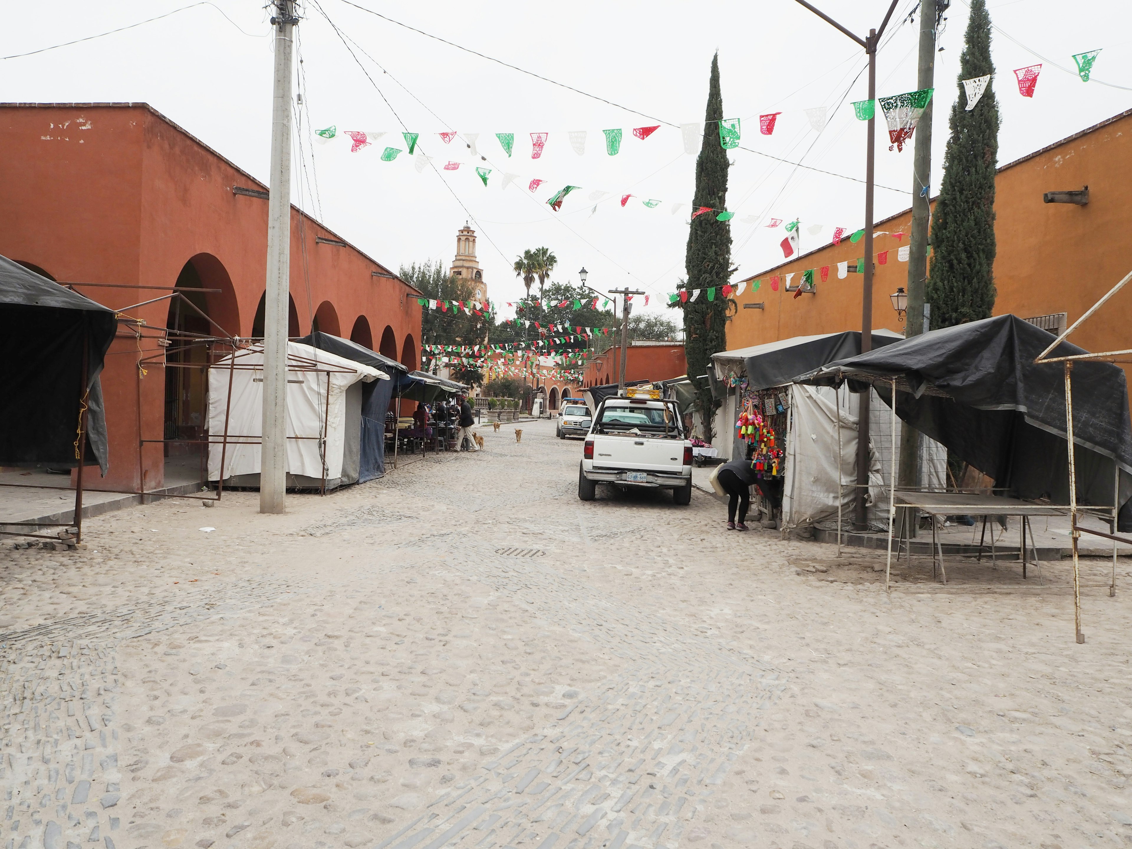 Scène de marché avec des bâtiments rouges et des tentes tour de cloche visible au loin