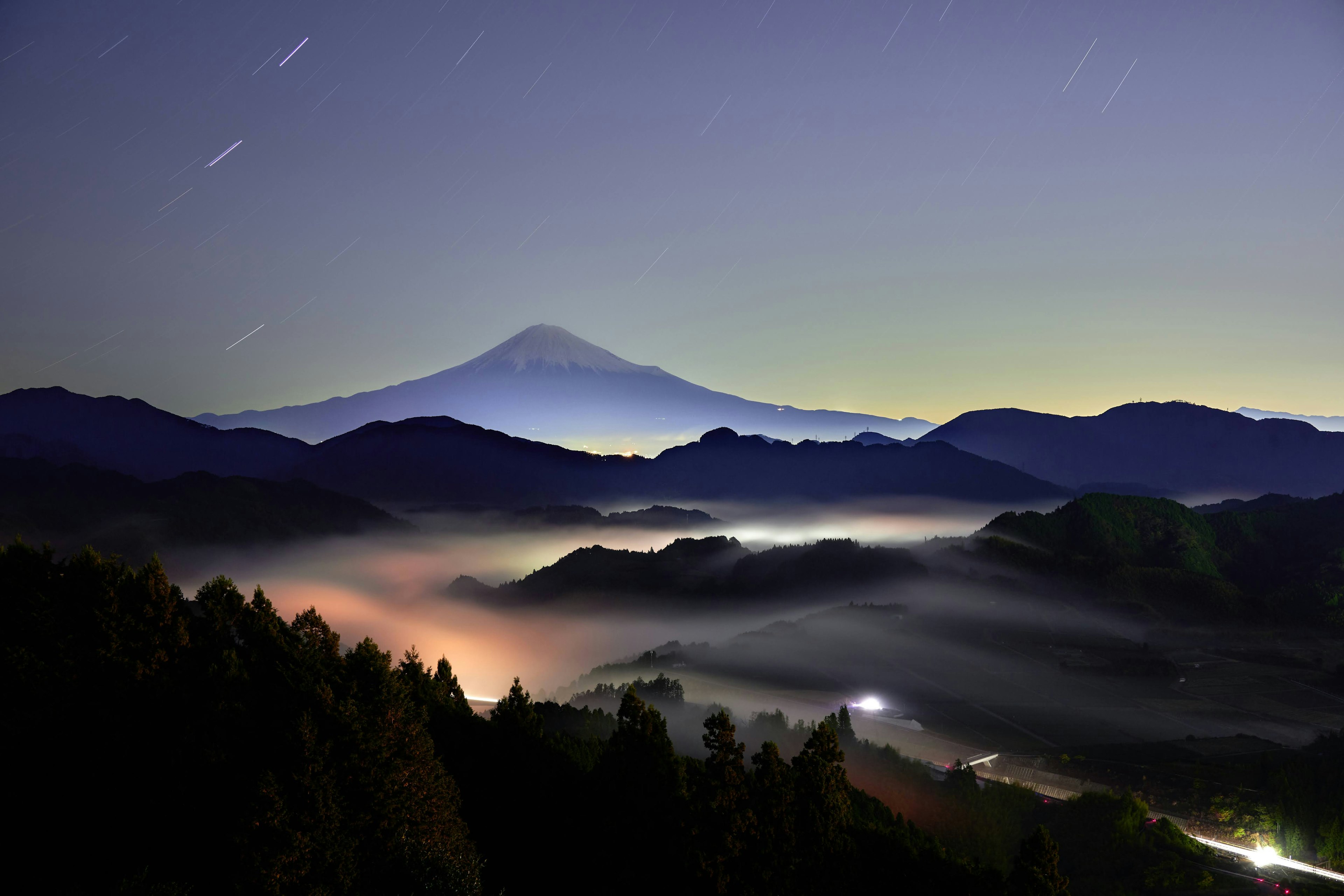 Vue nocturne magnifique du mont Fuji entouré de montagnes brumeuses