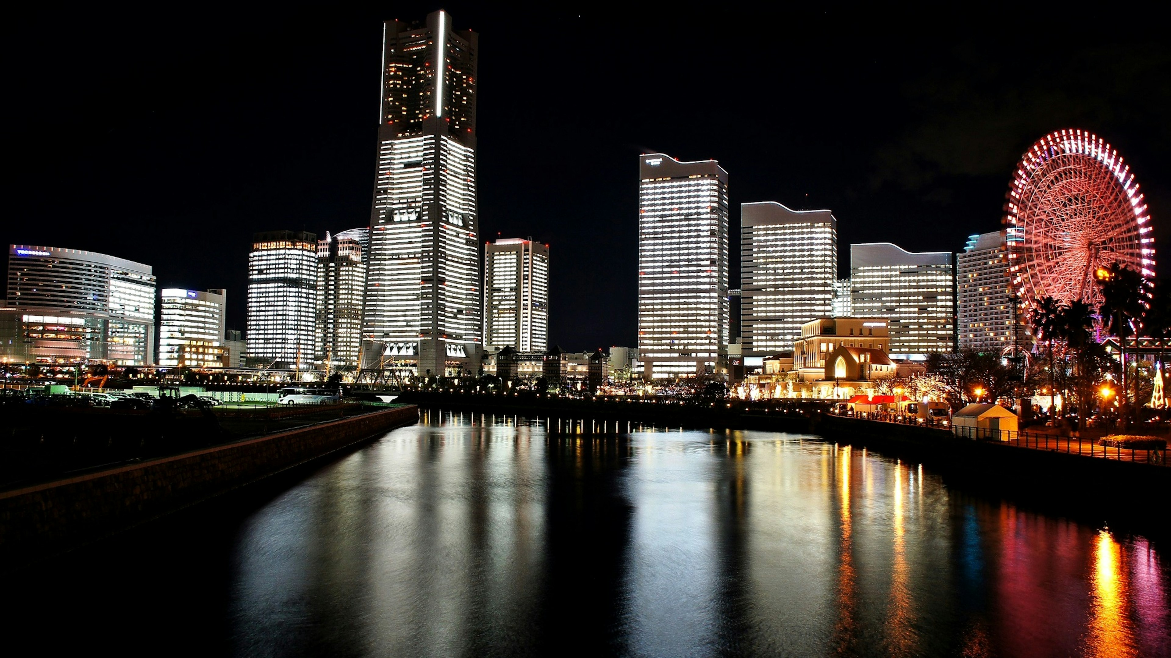 Paisaje urbano nocturno con edificios brillantes y una noria