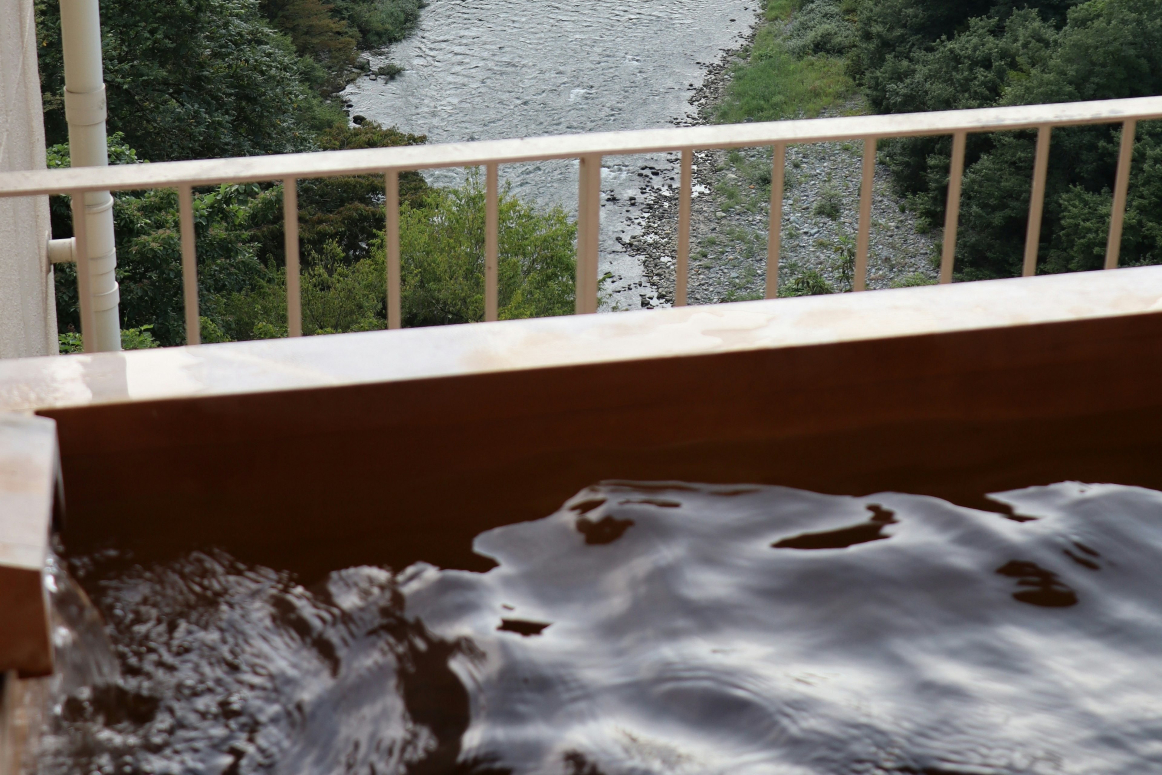 川の景色を望む木製の浴槽とその水面