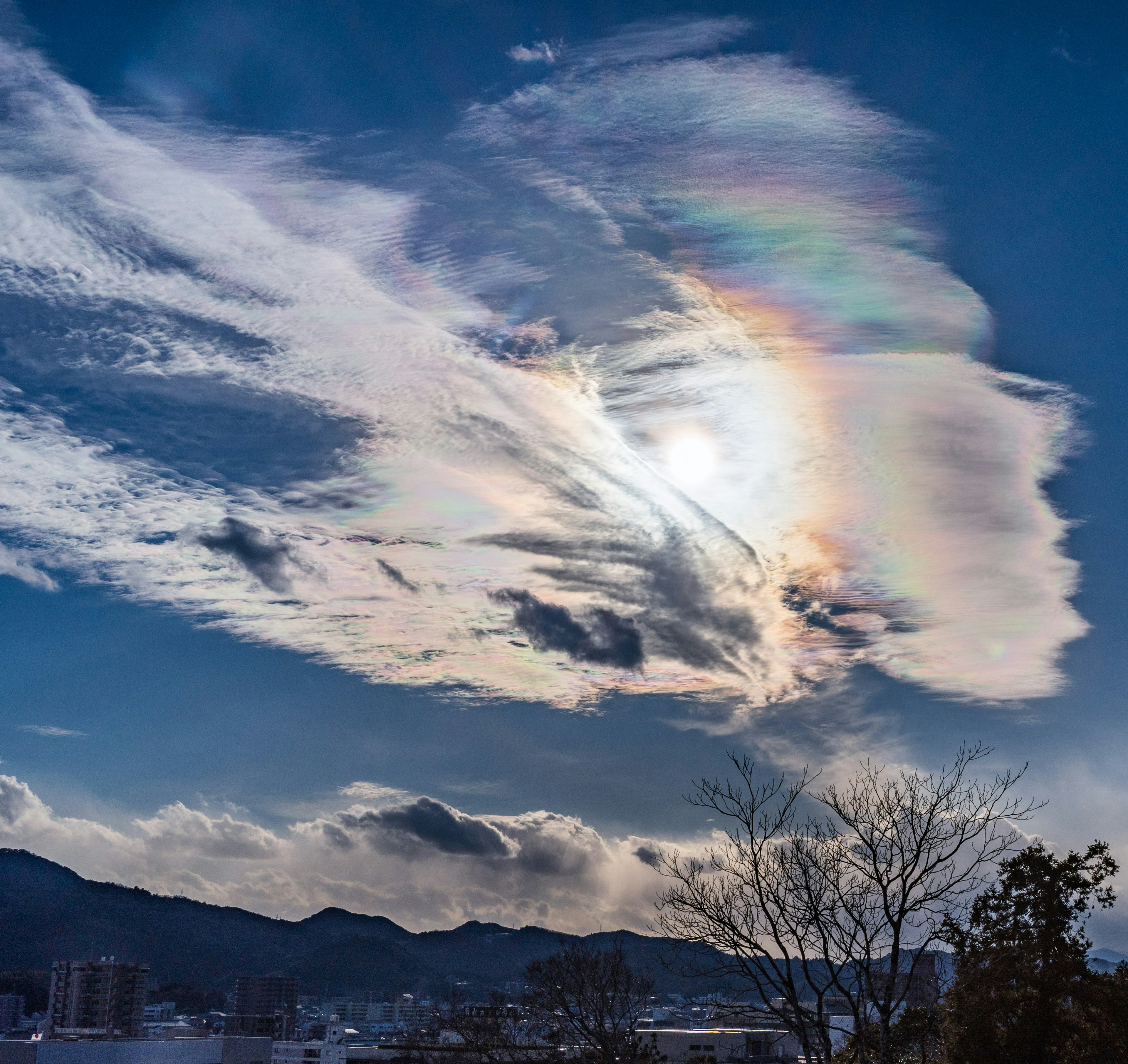 青空に浮かぶ虹色の雲と太陽の光が美しい風景