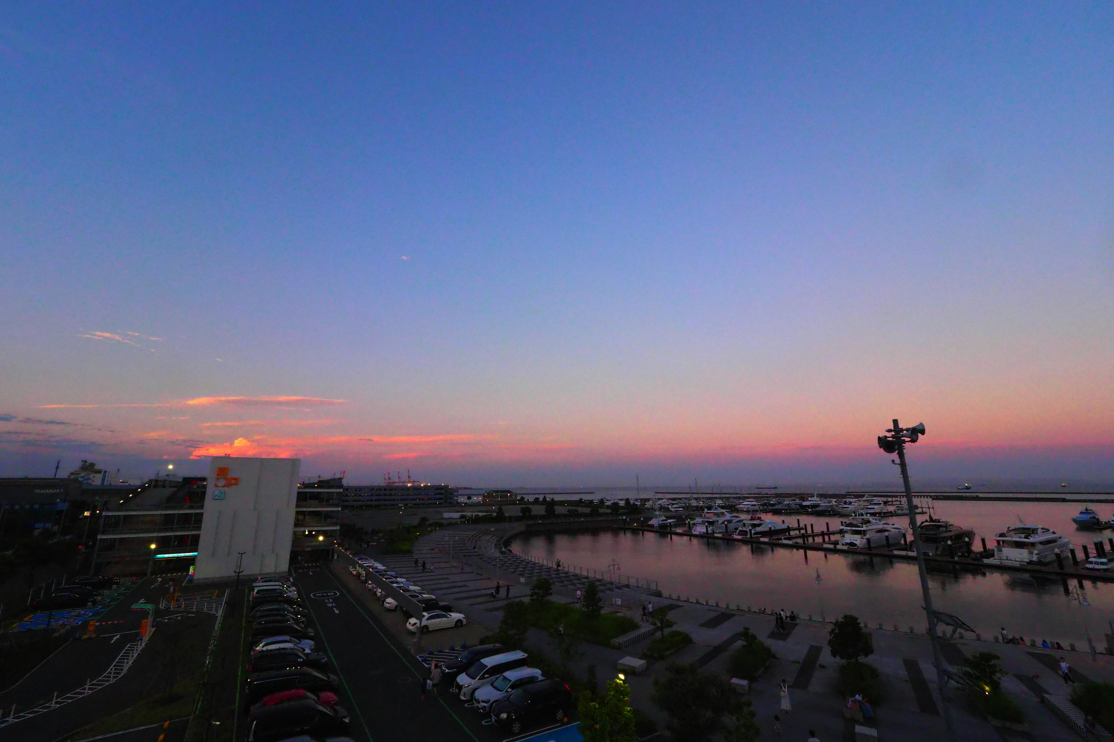 Coucher de soleil sur un port avec des voitures garées et des bâtiments