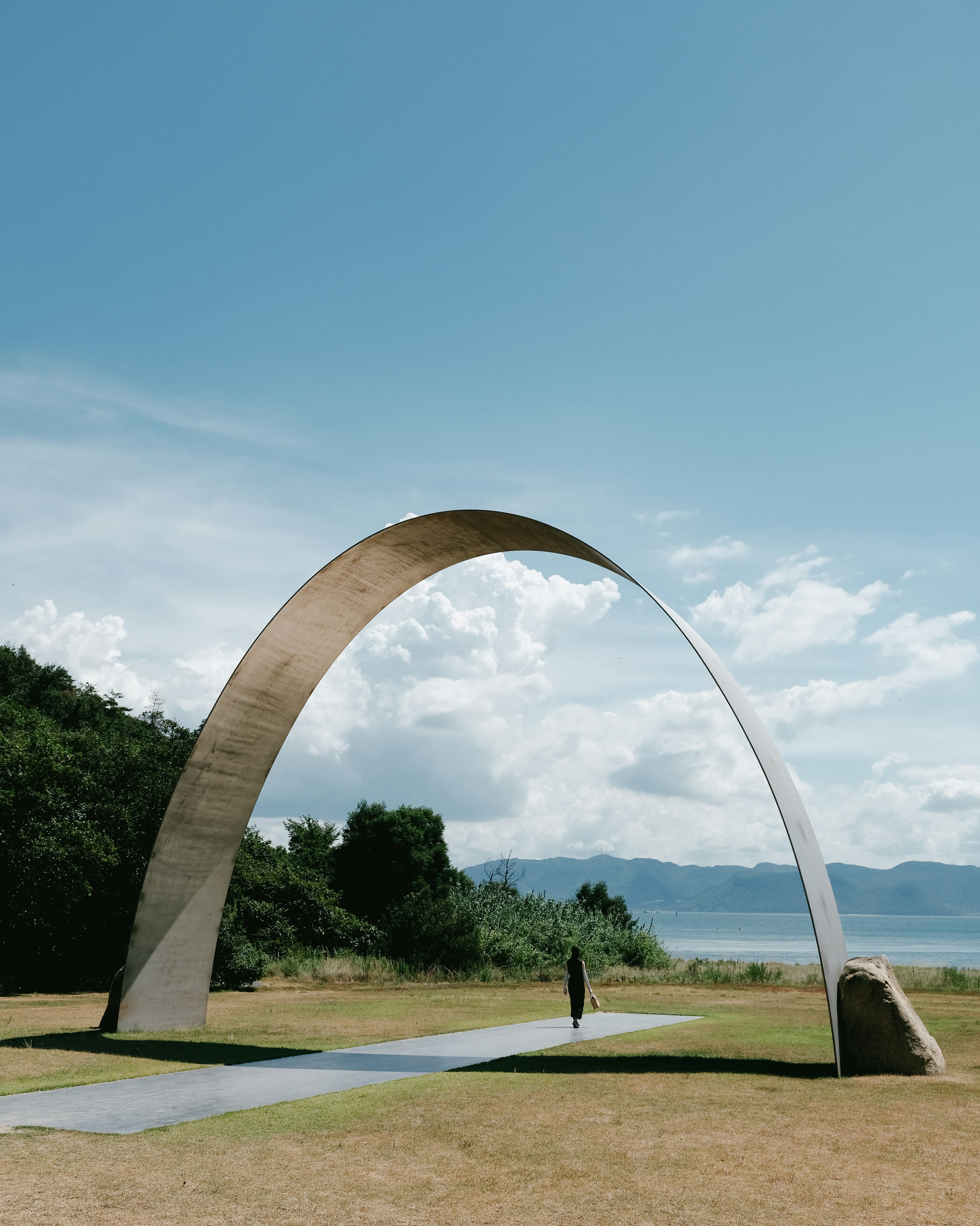 A large arch-shaped sculpture stands under a blue sky