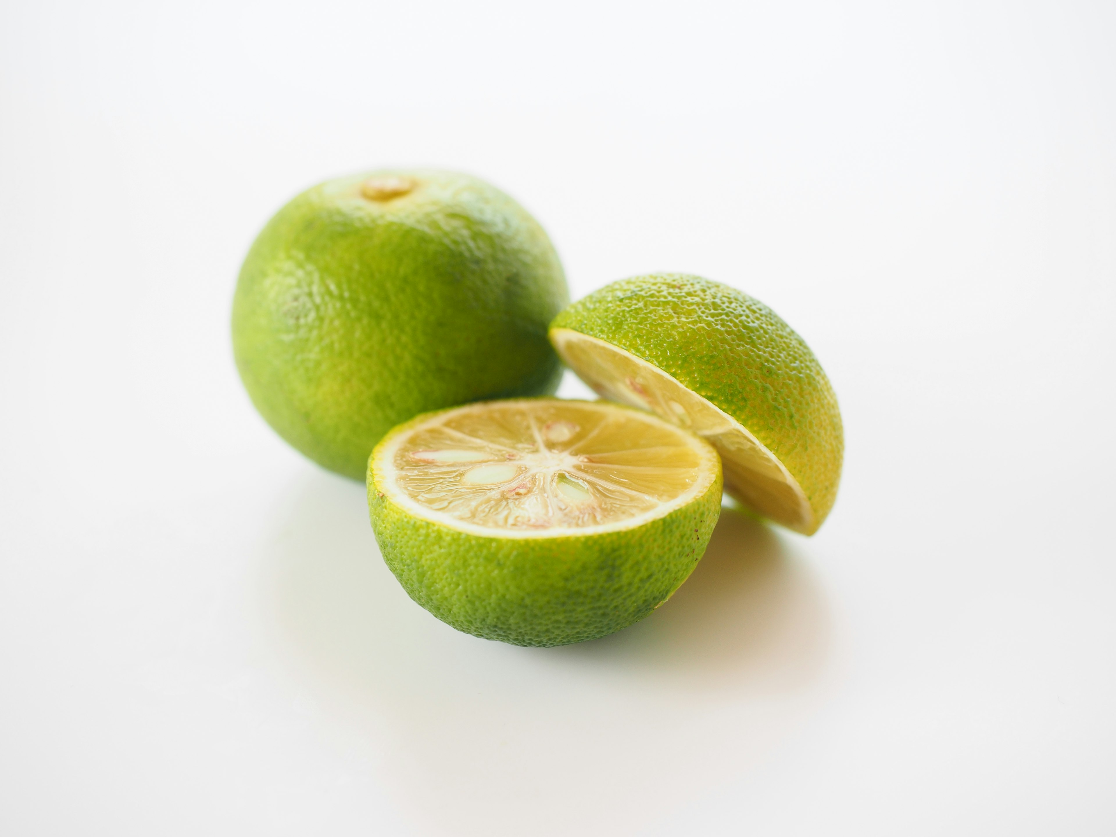 Green limes with one cut in half on a white background