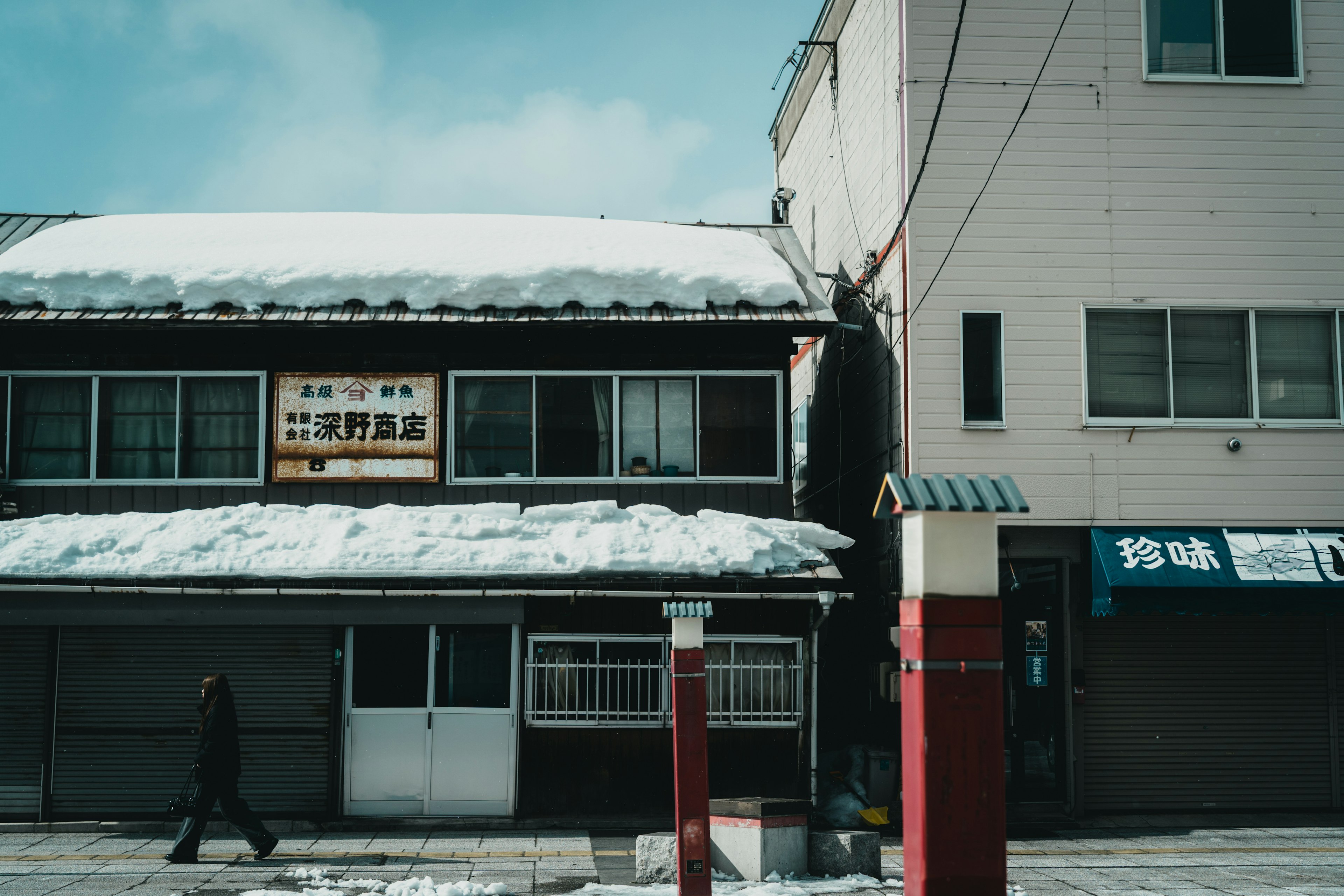 Edificio japonés tradicional con nieve y edificio moderno al lado