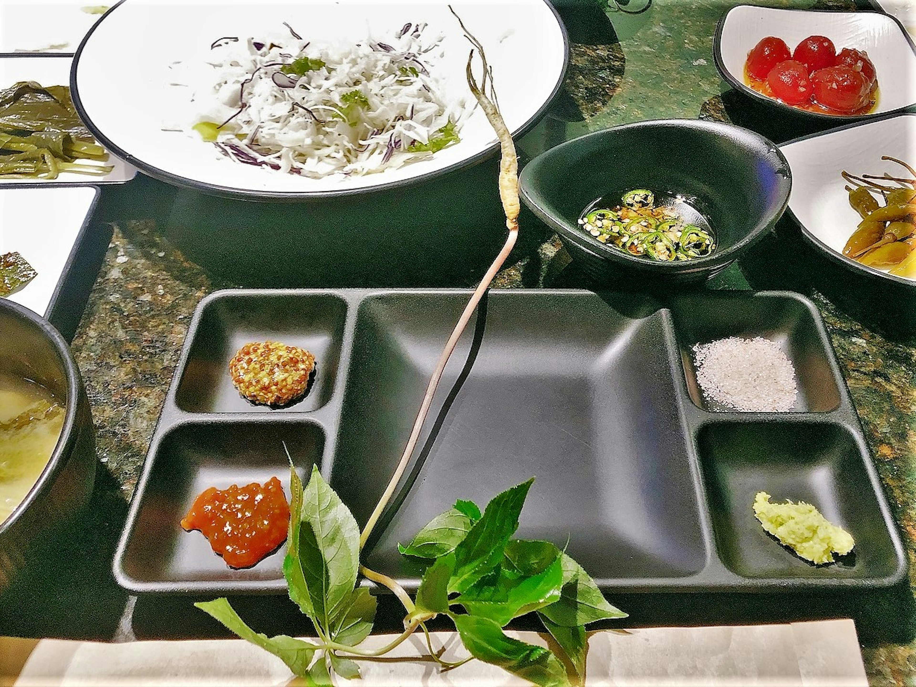 Japanese appetizer and condiments arranged on a black plate