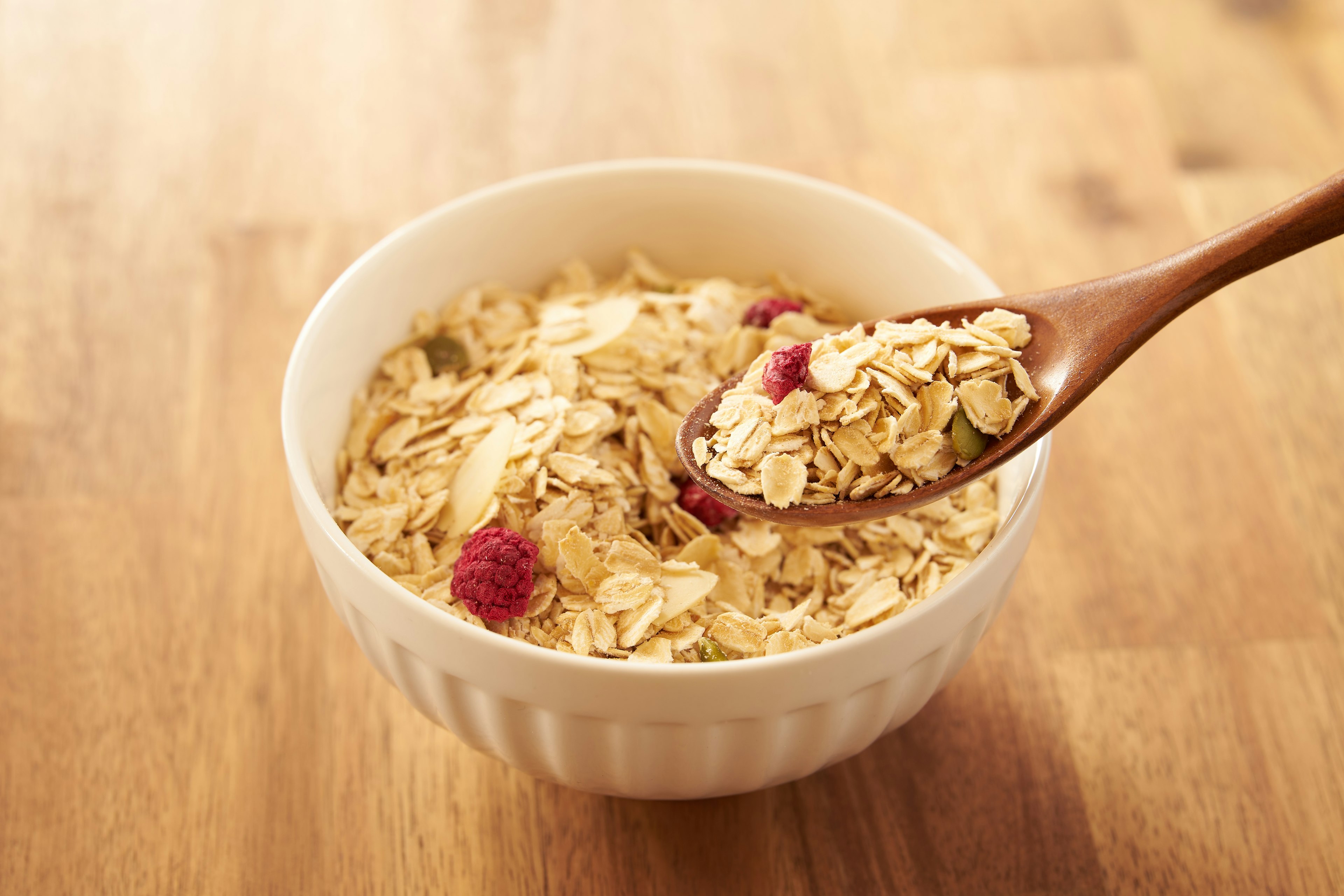 Oatmeal in a white bowl with a wooden spoon