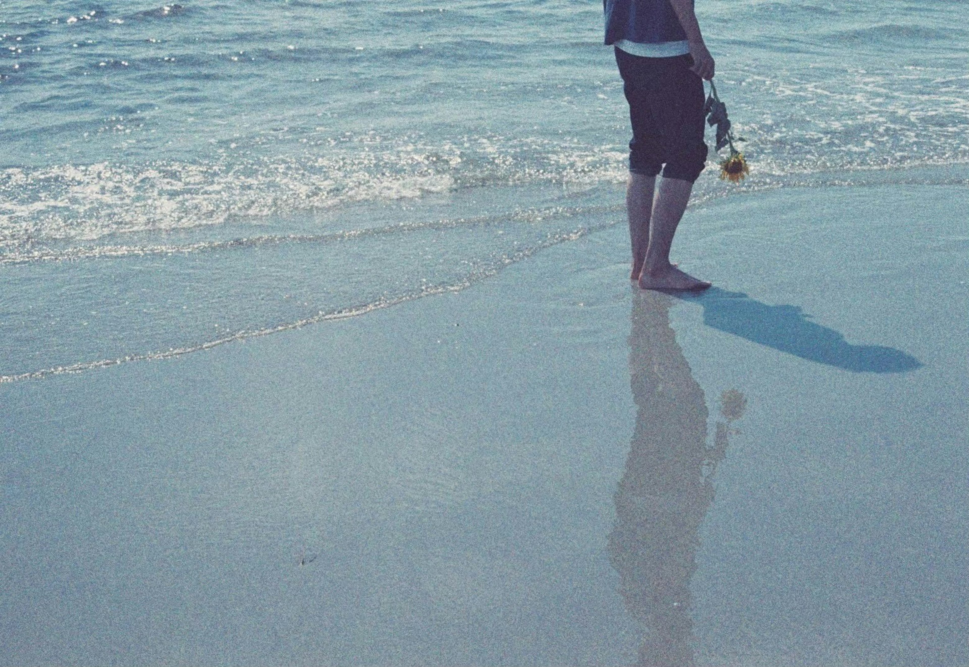 Persona in piedi sulla spiaggia con ombra e onde