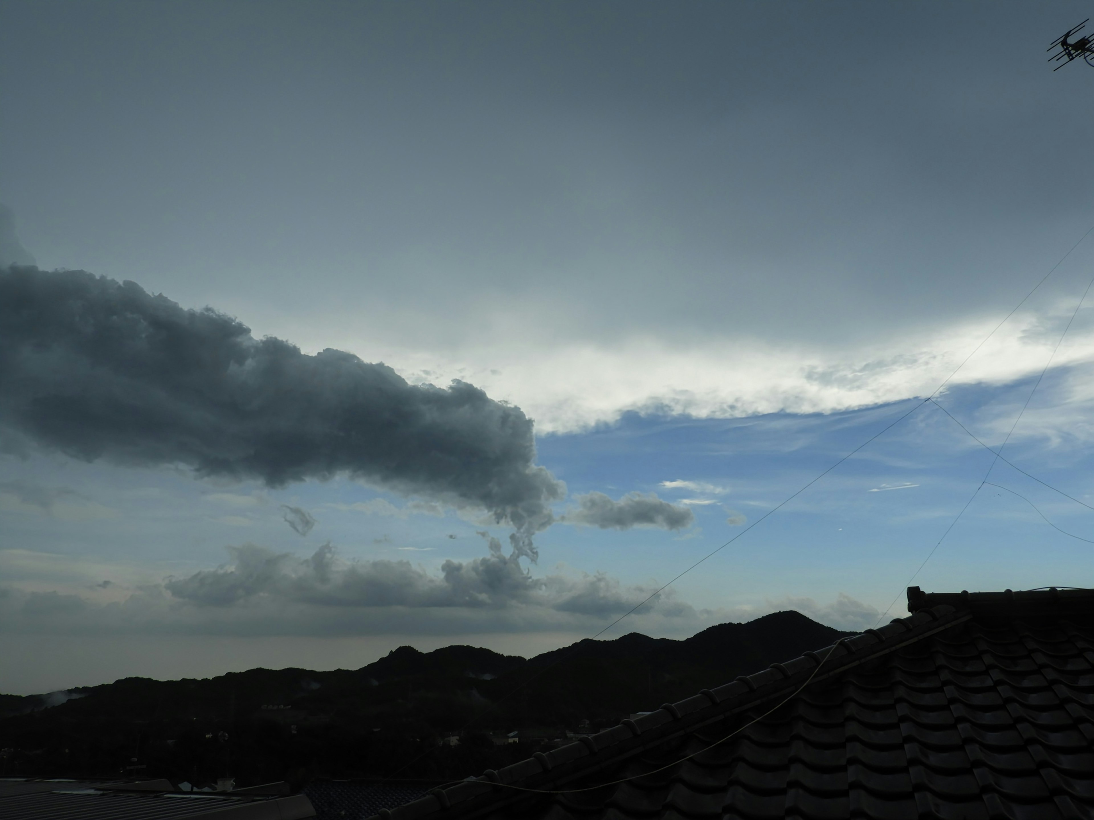 Pemandangan dengan langit biru dan awan di atas atap