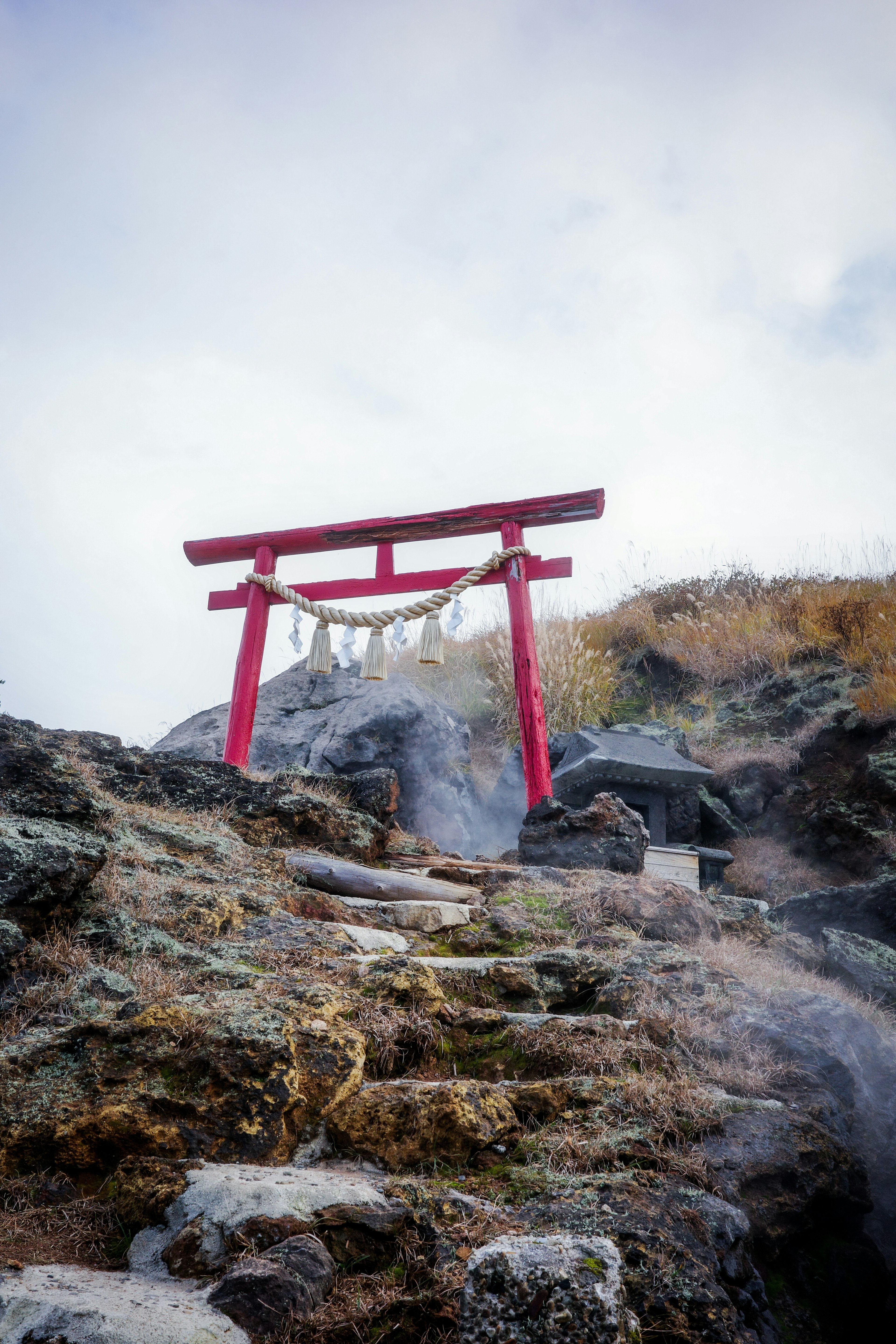 赤い鳥居が岩の上に立つ風景