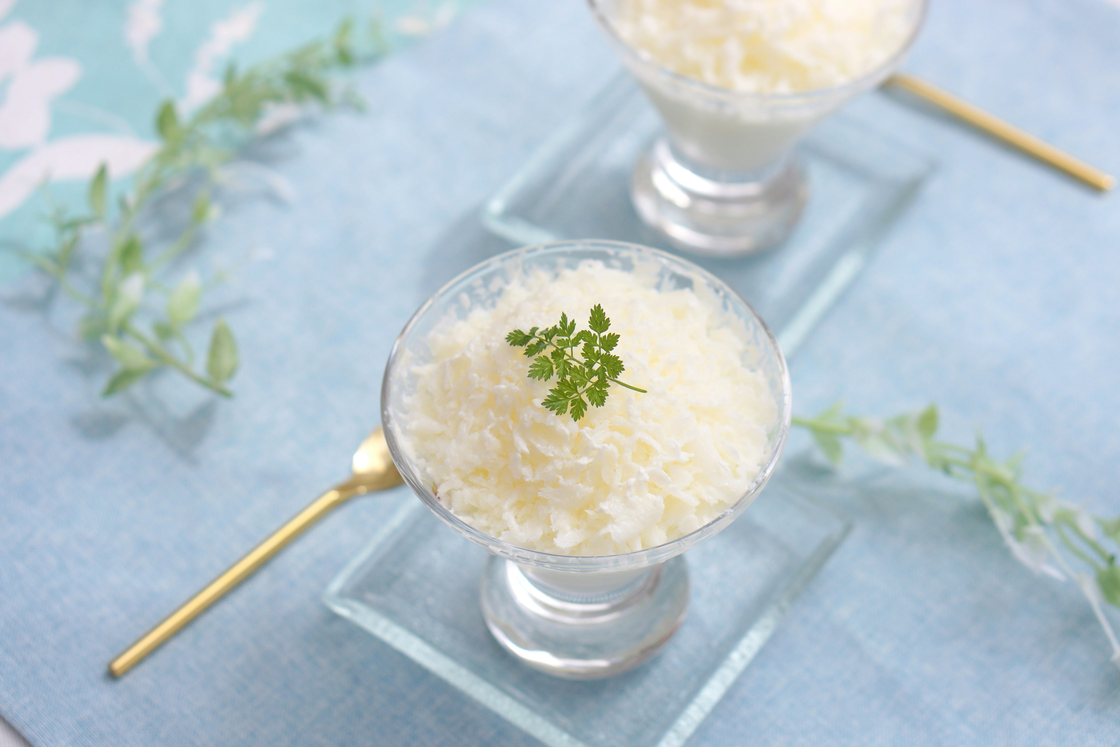 White dessert served in glass with a small herb garnish