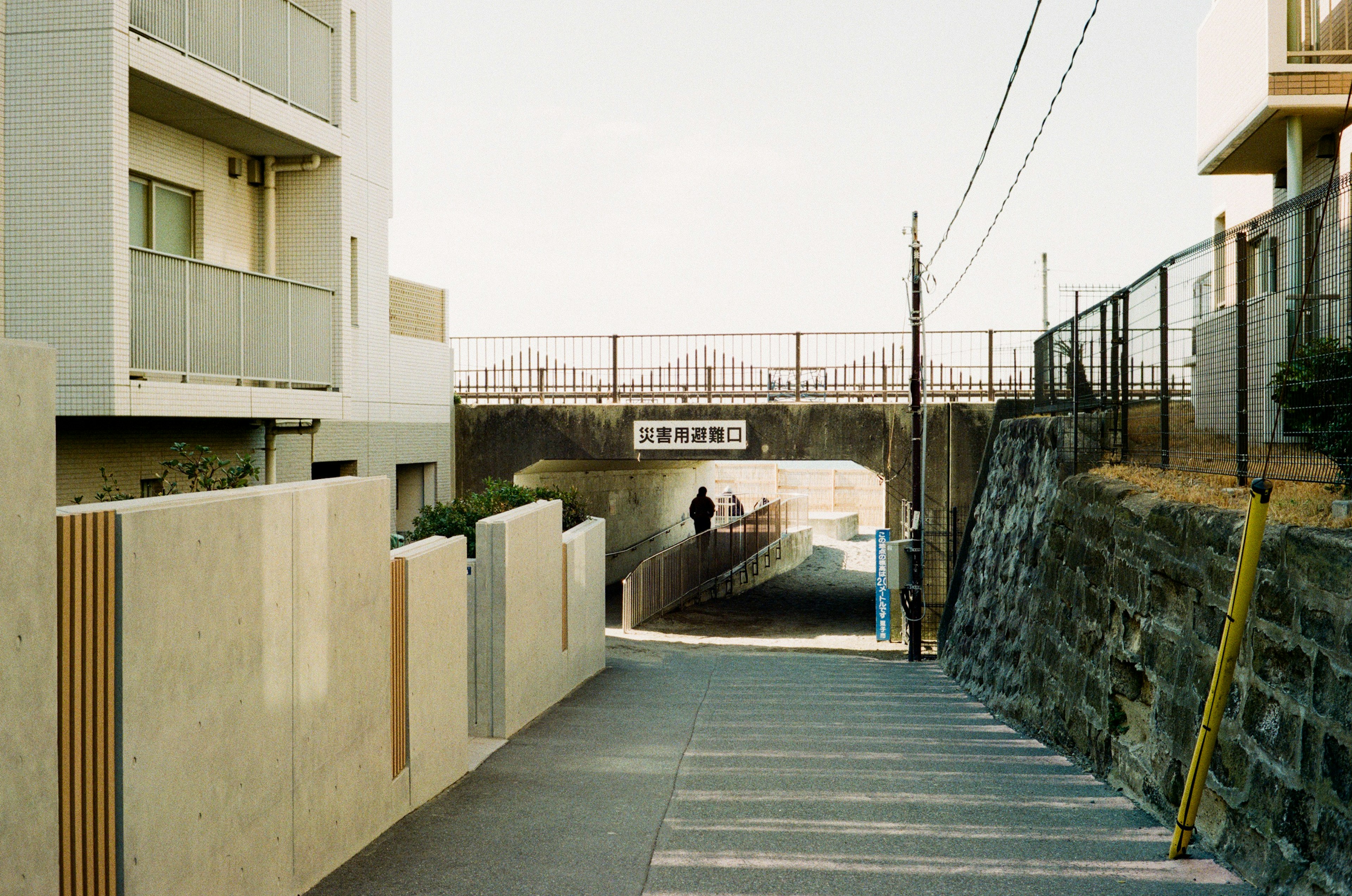 Quiet street scene with residential buildings and an overpass in the background