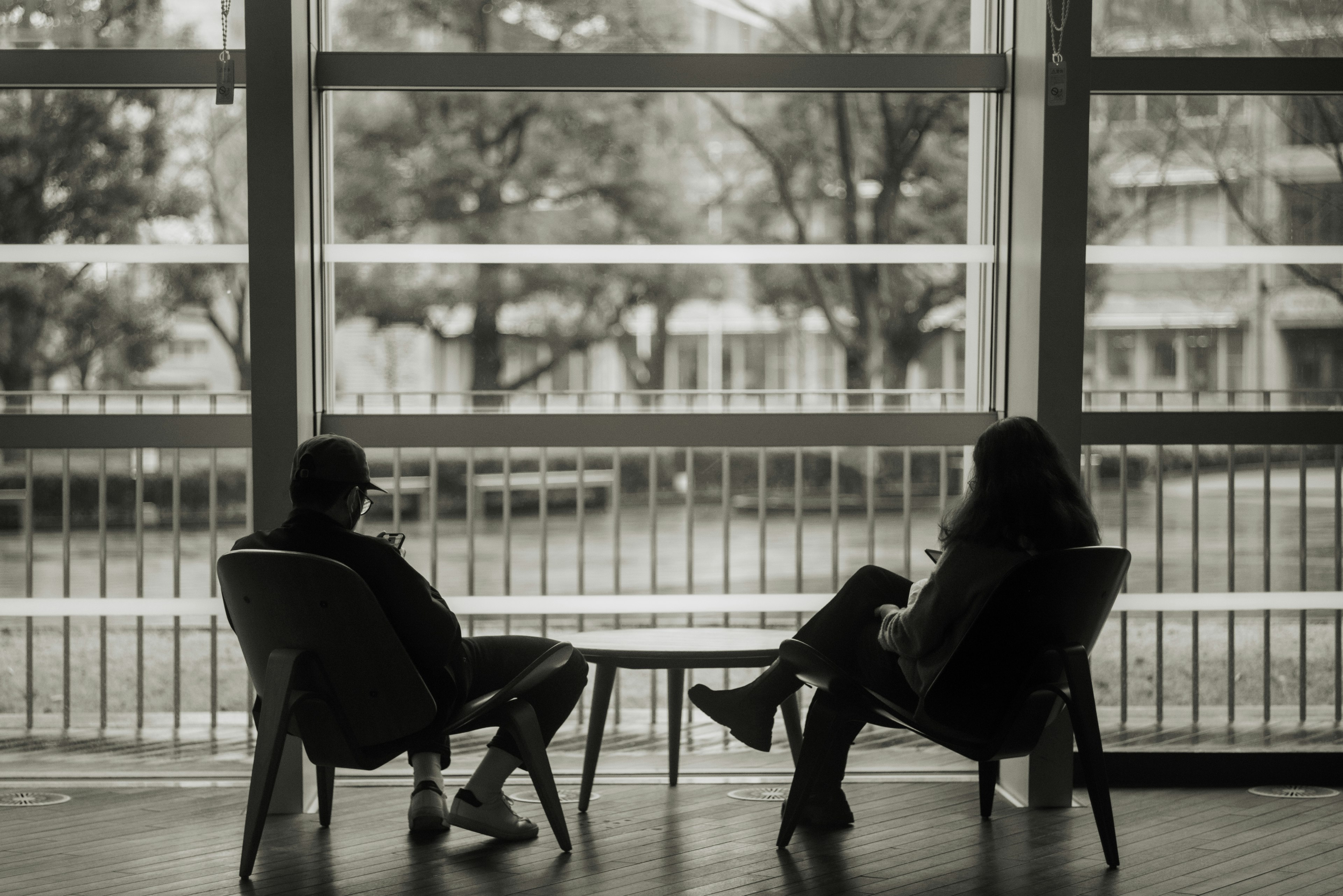 Dos personas sentadas cerca de una ventana con vista verde