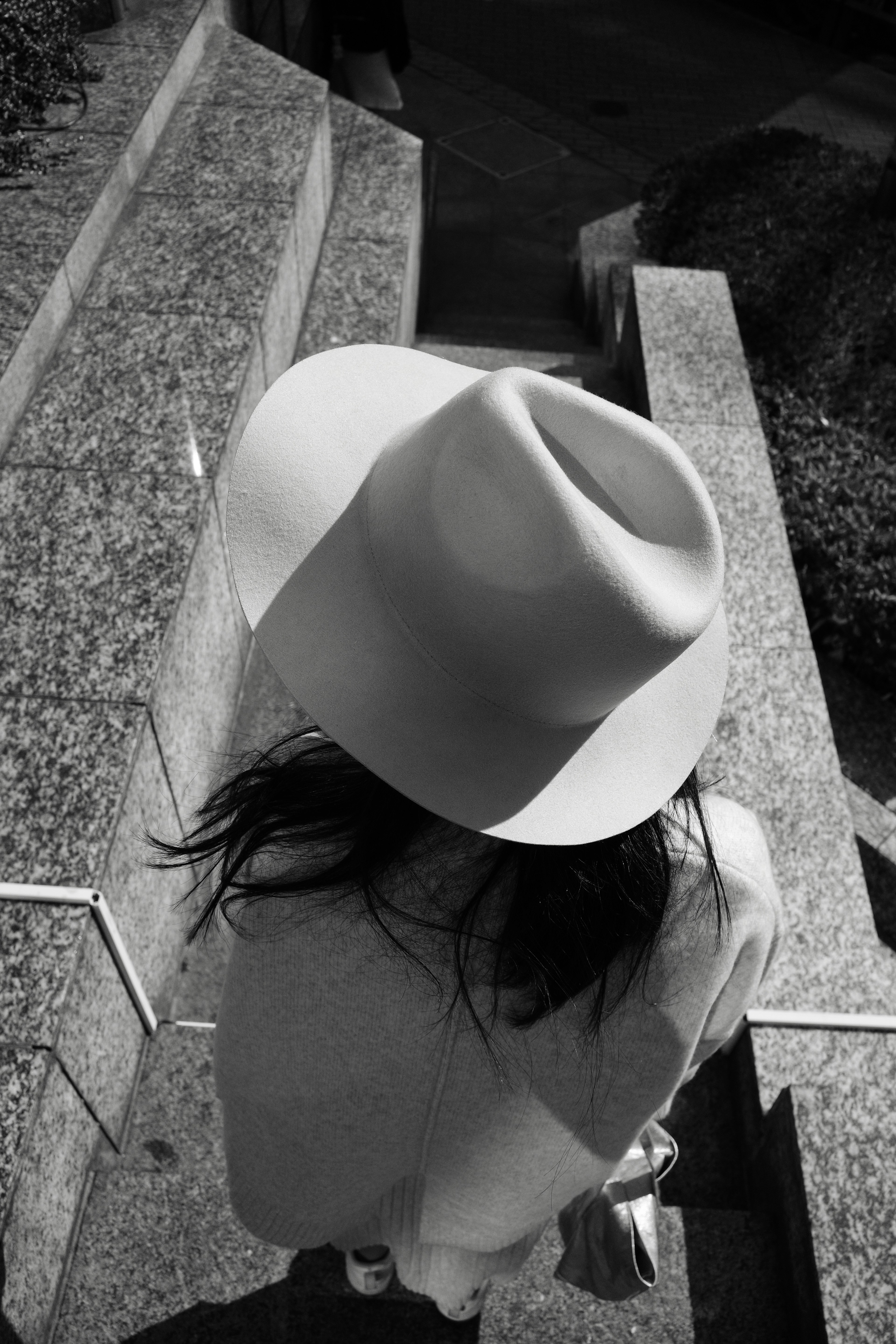 Une femme descendant des escaliers avec un chapeau blanc