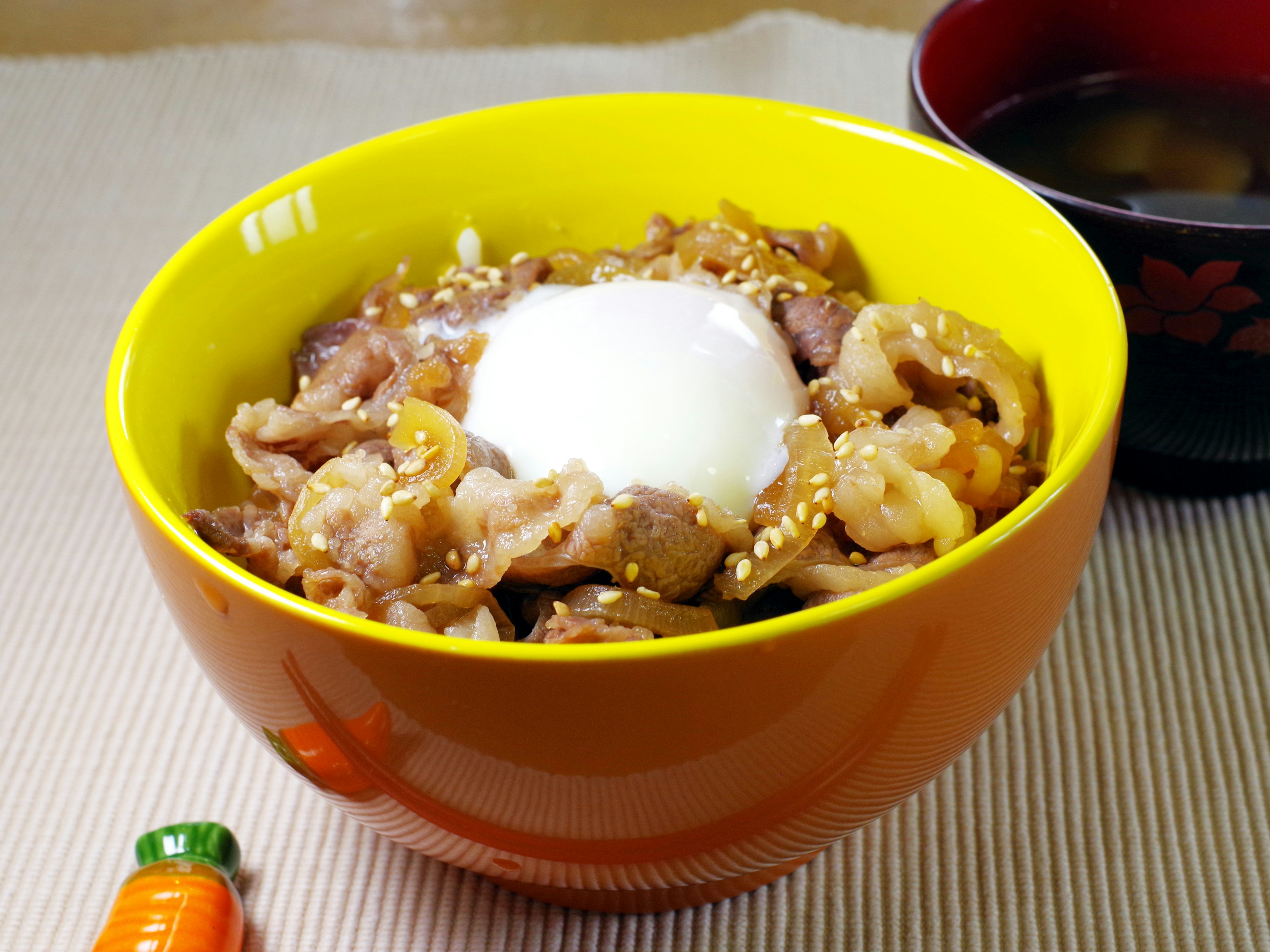 A yellow bowl filled with meat and an egg dish