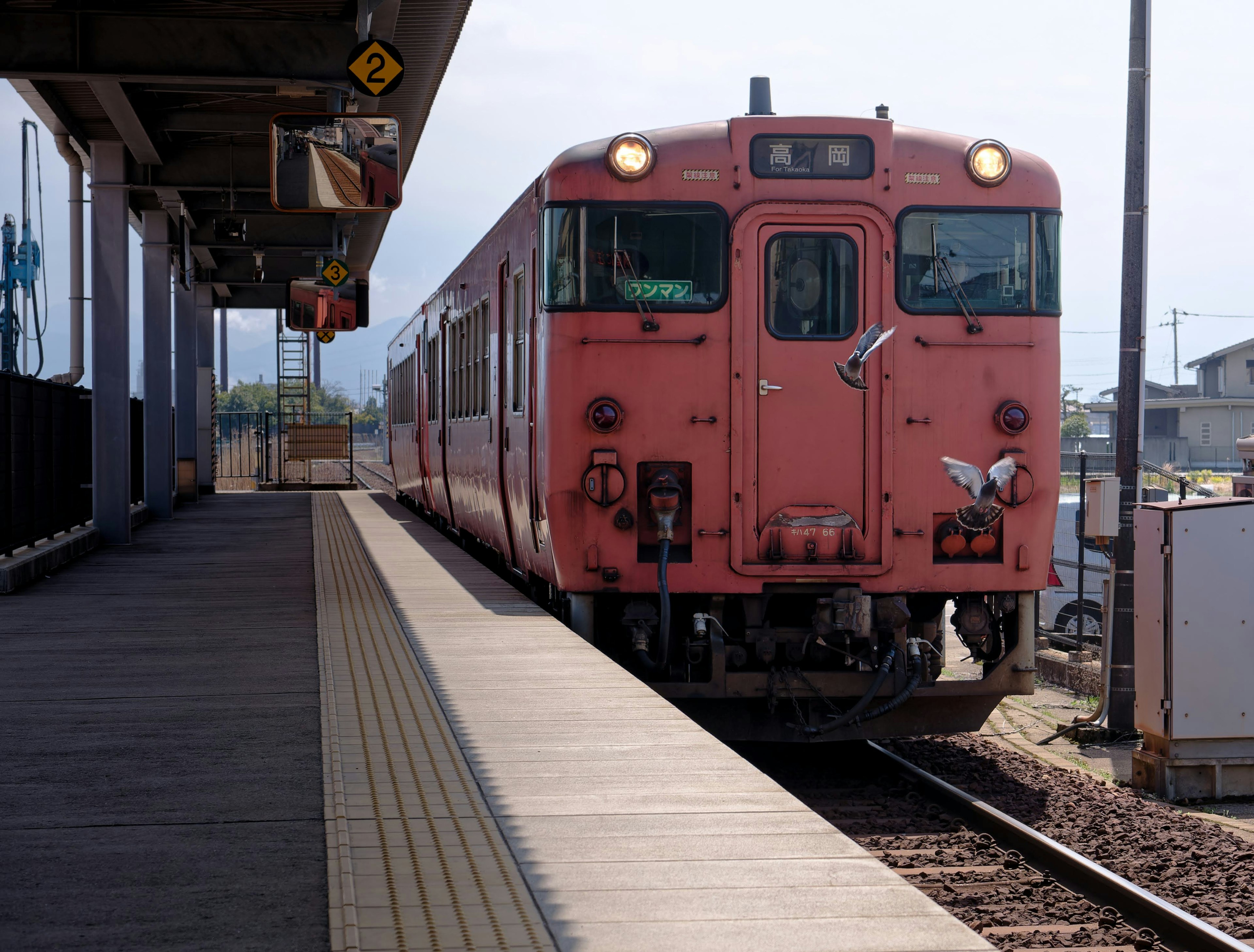 A pink train arriving at a station