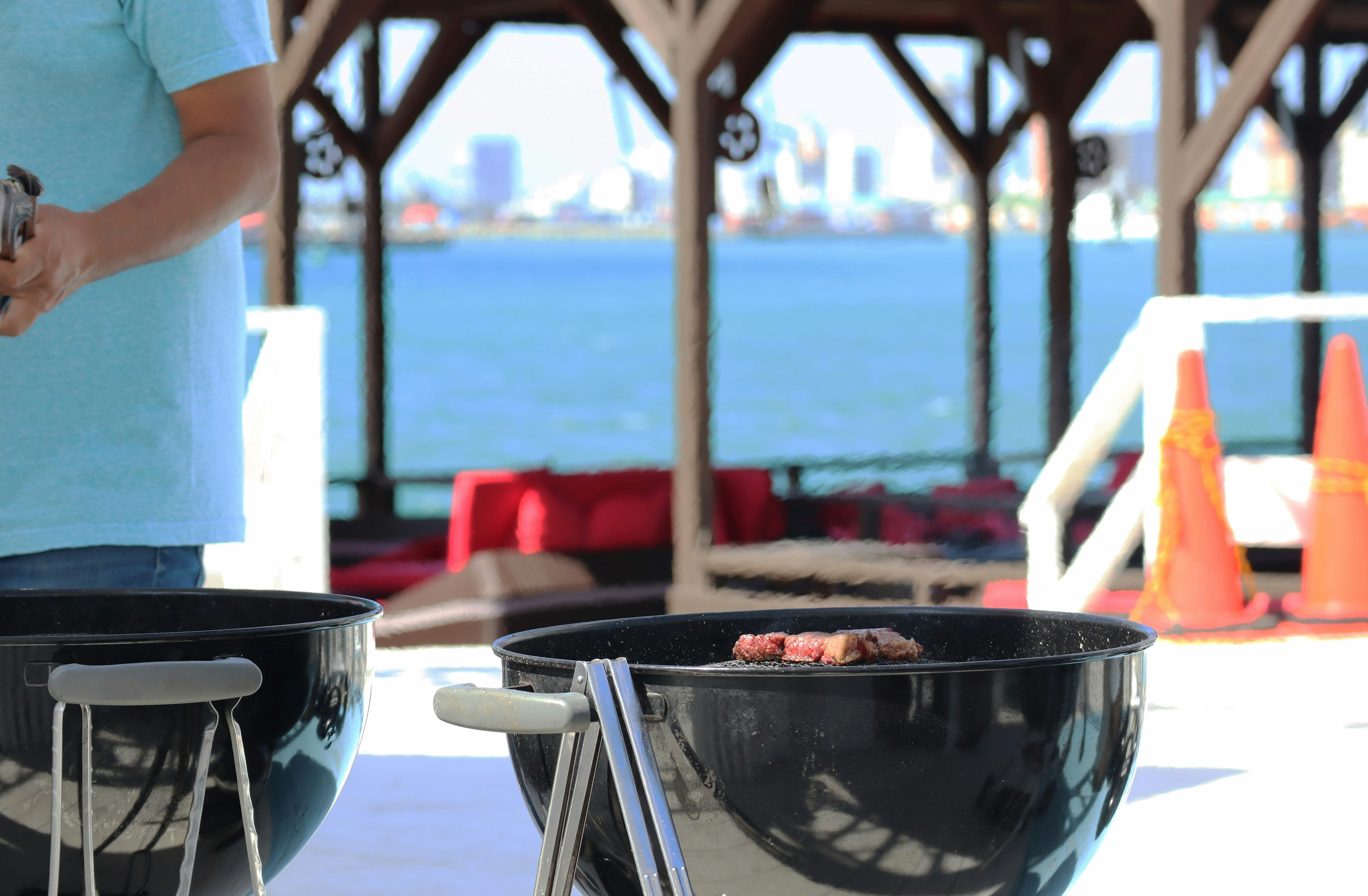 Scene of enjoying barbecue near the sea with barbecue grills and city skyline in the background