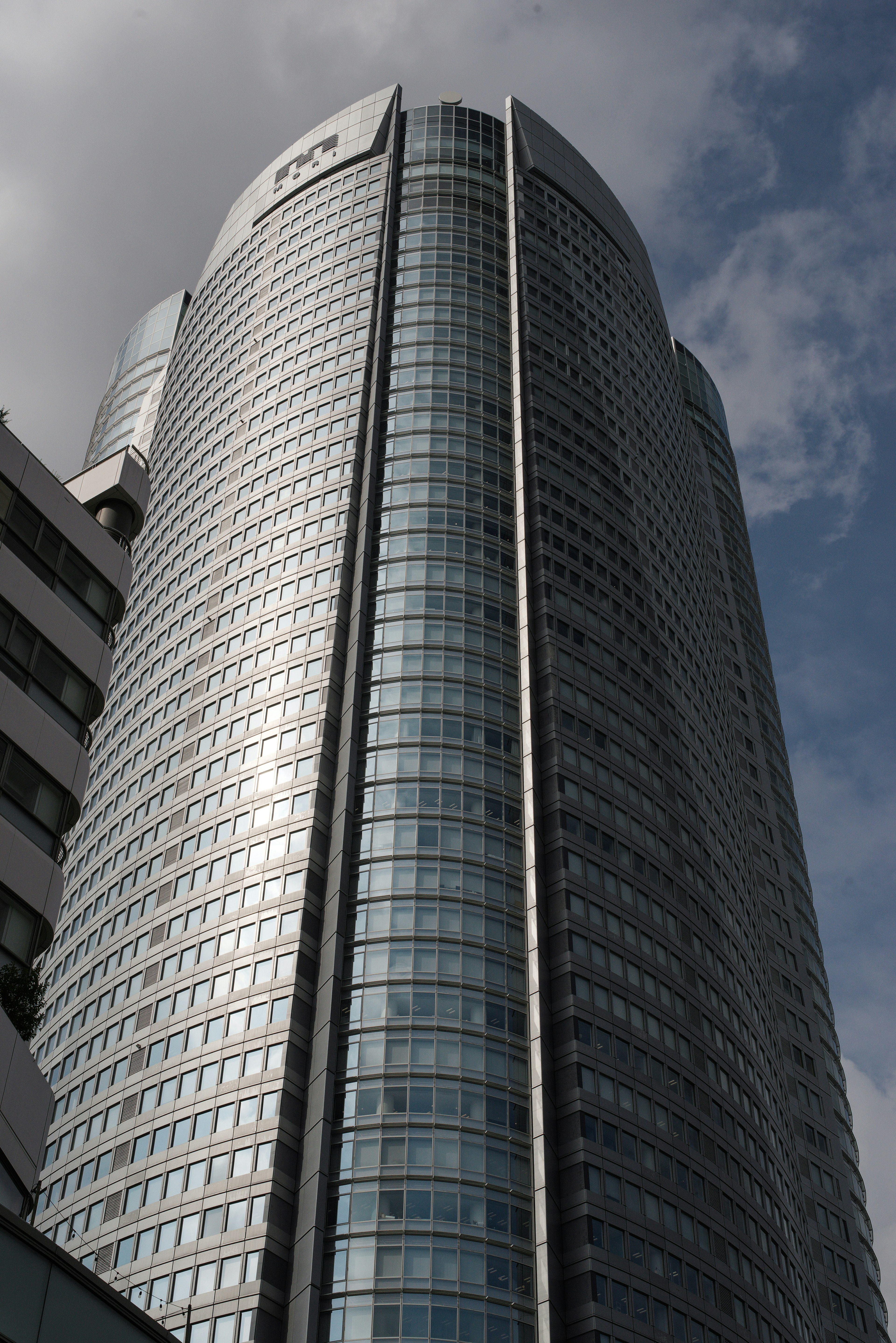 高層建築特寫，玻璃外立面在陰雲天空下