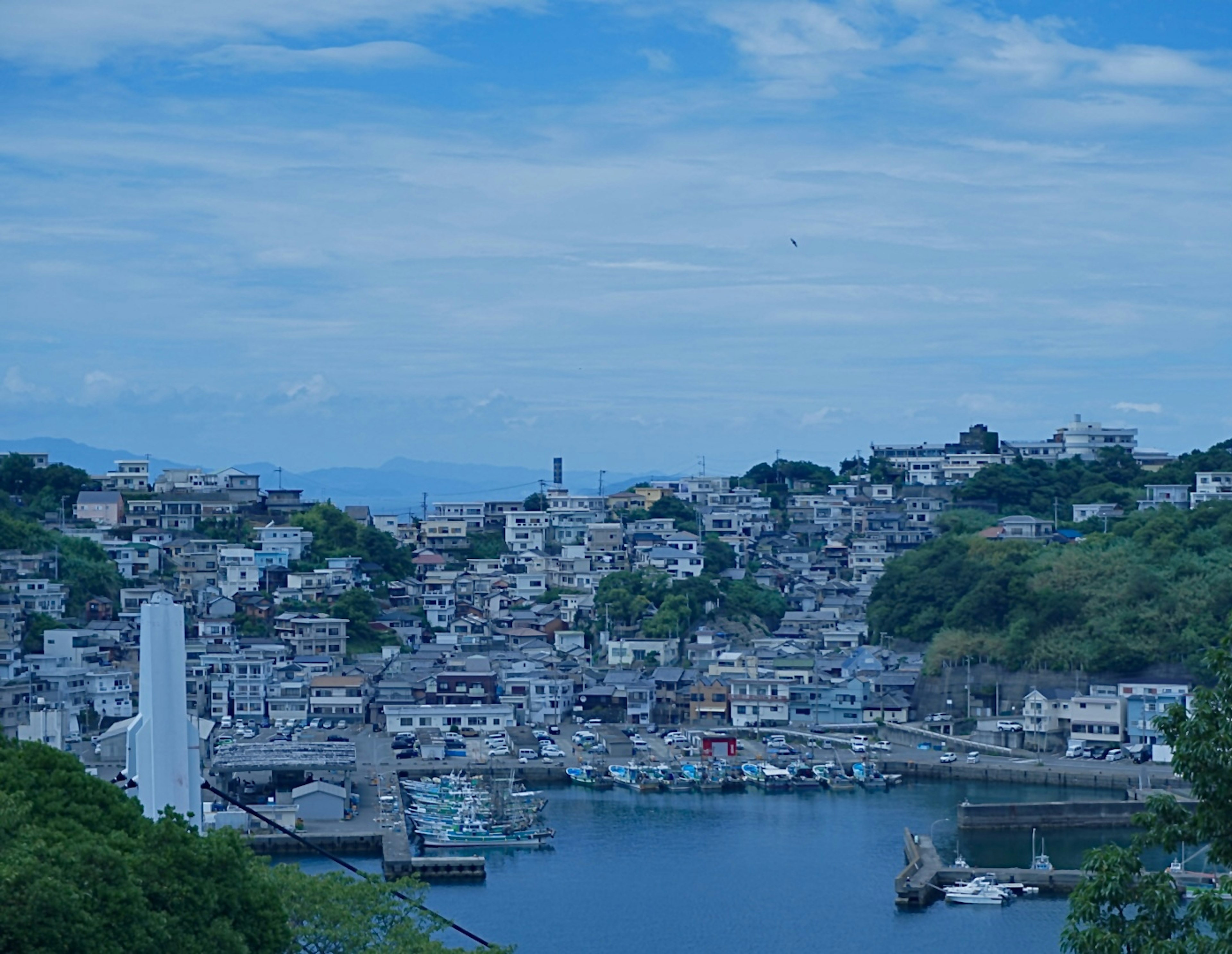 Scenic view of a coastal town under blue sky featuring clustered houses and harbor