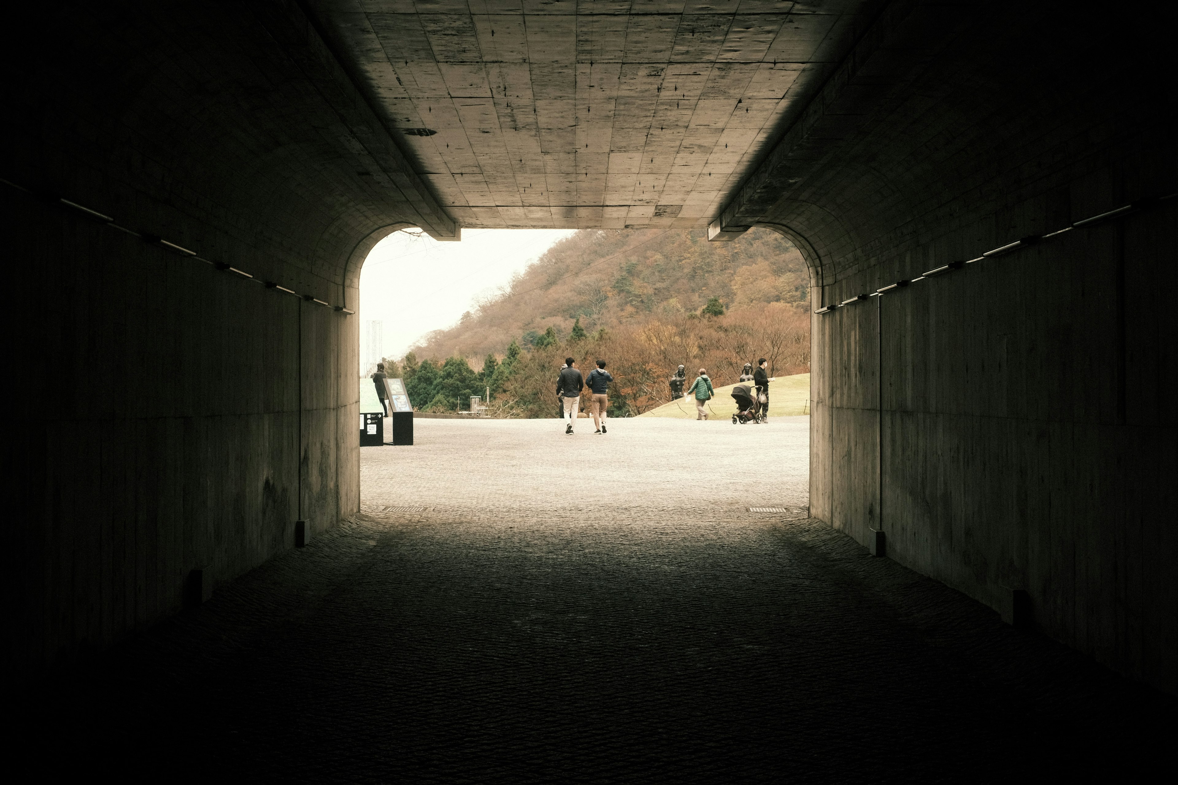 Blick auf eine Landschaft und Silhouetten von Menschen durch einen Tunnel