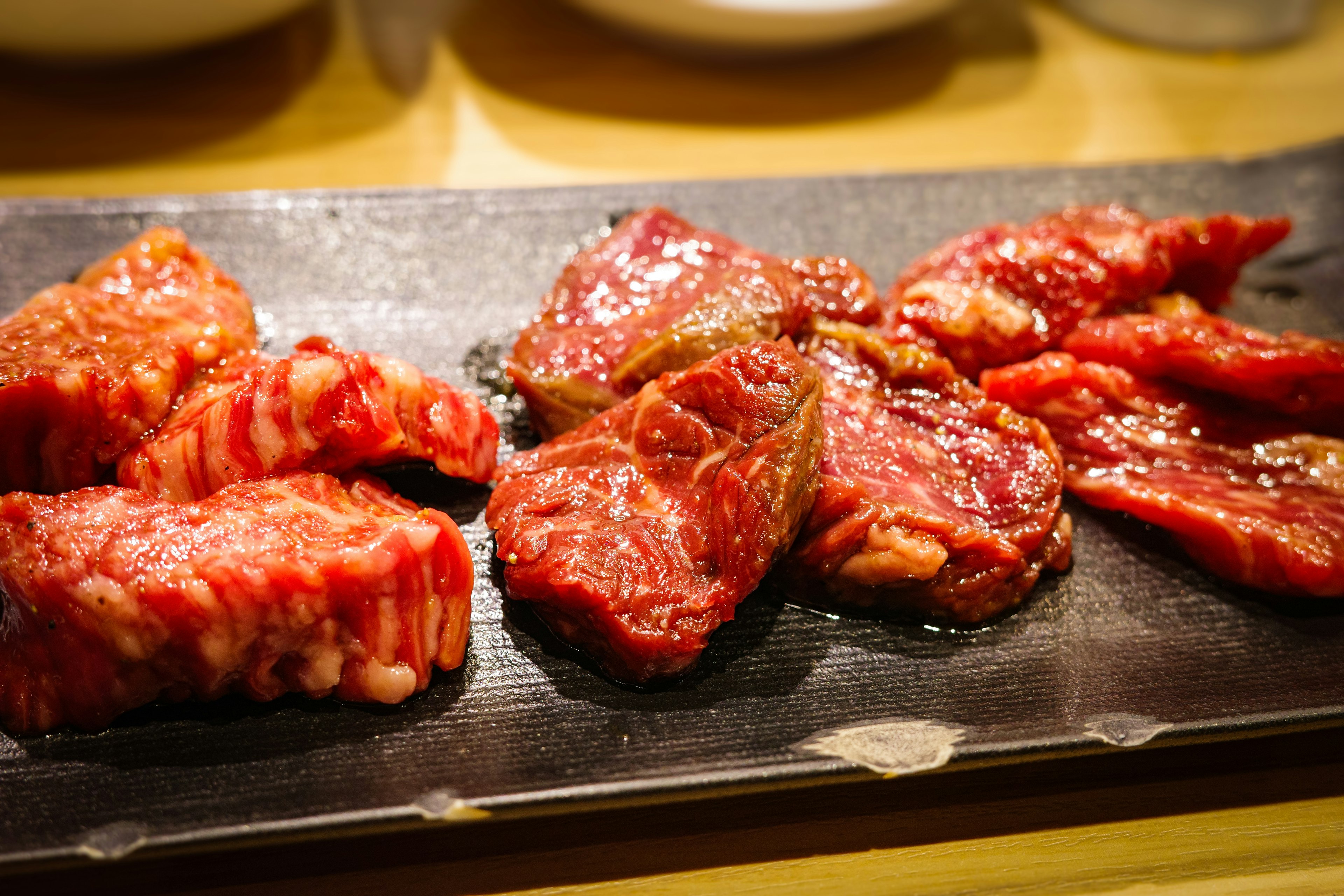 Platter of assorted raw meat for grilling including marbled beef and lean cuts