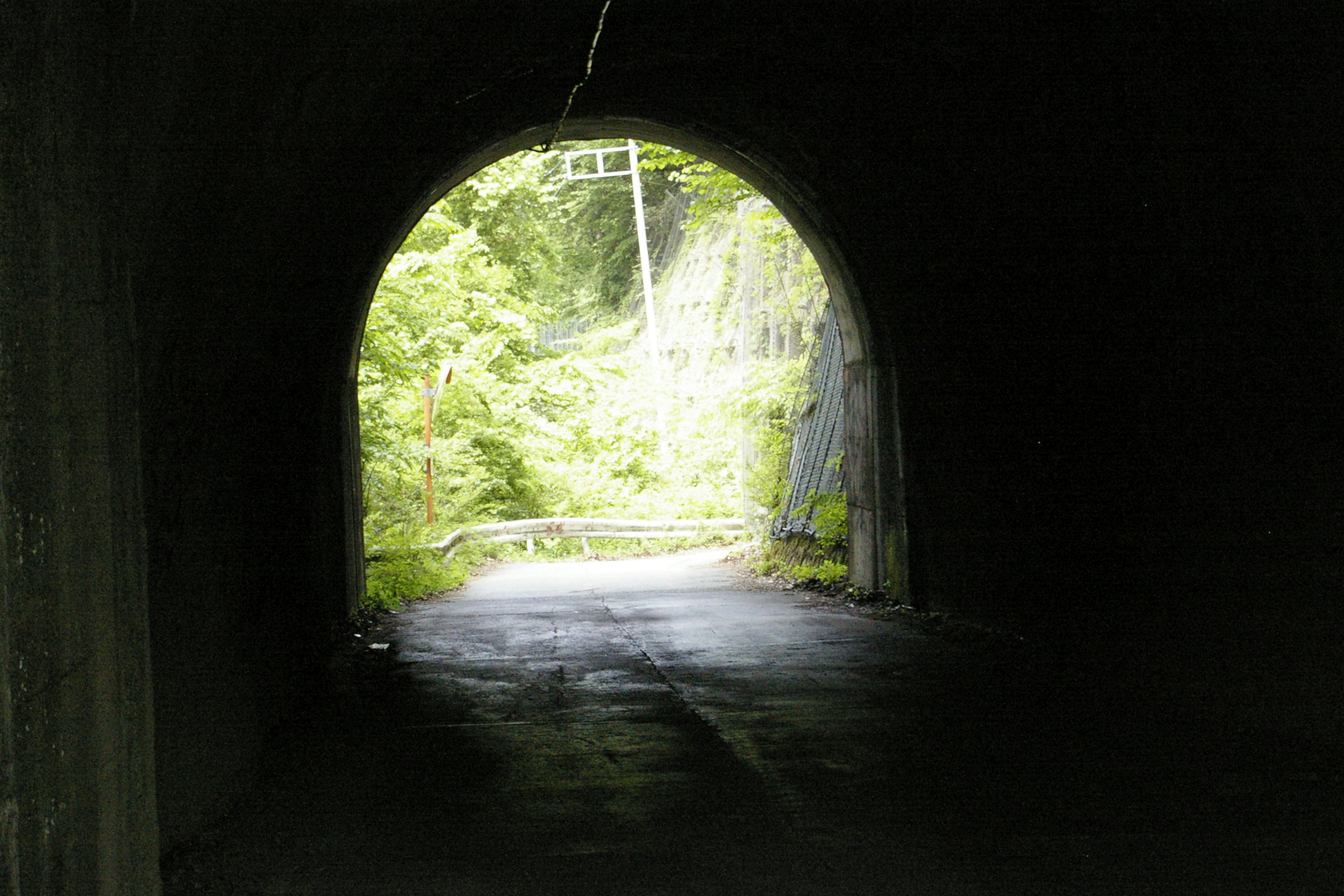 A dark tunnel leading to a bright green landscape