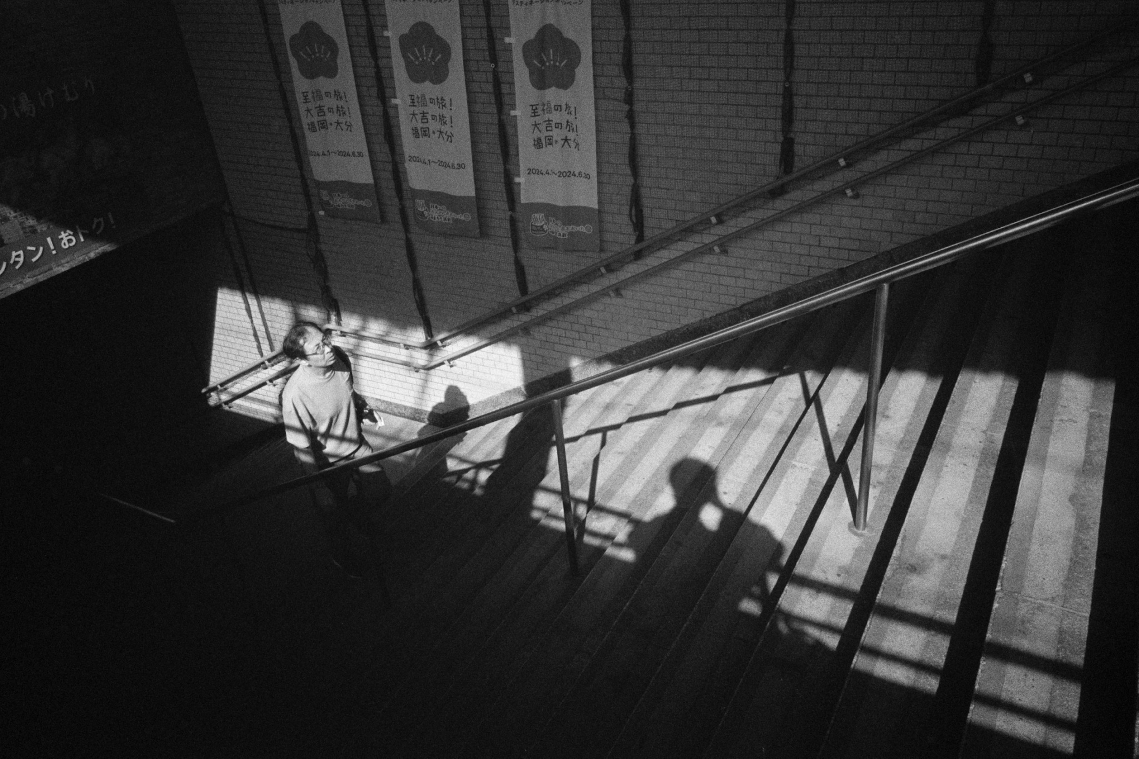 Foto en blanco y negro de sombras y luz en escaleras con una persona bajando