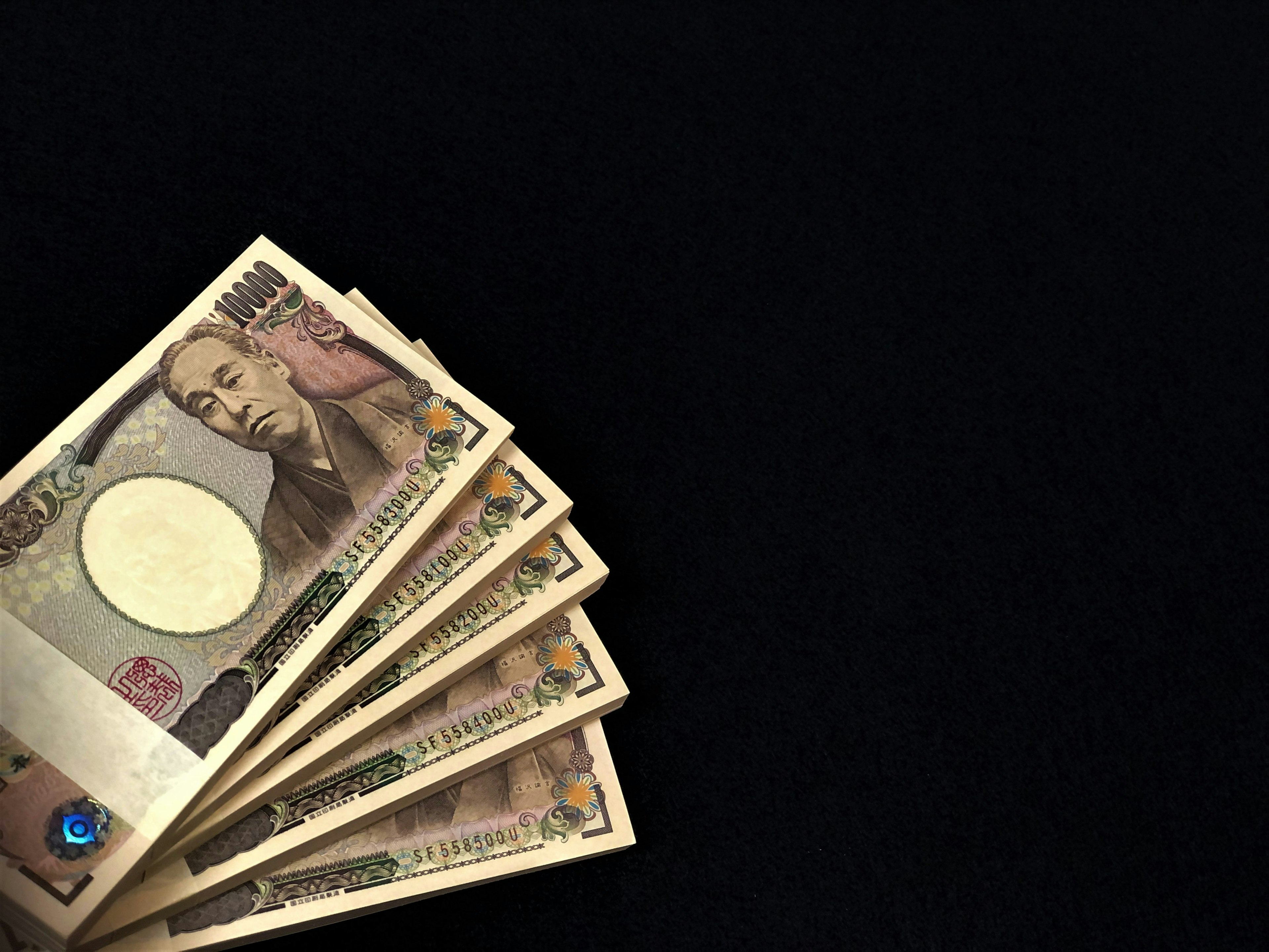 Japanische Yen-Banknoten auf schwarzem Hintergrund angeordnet