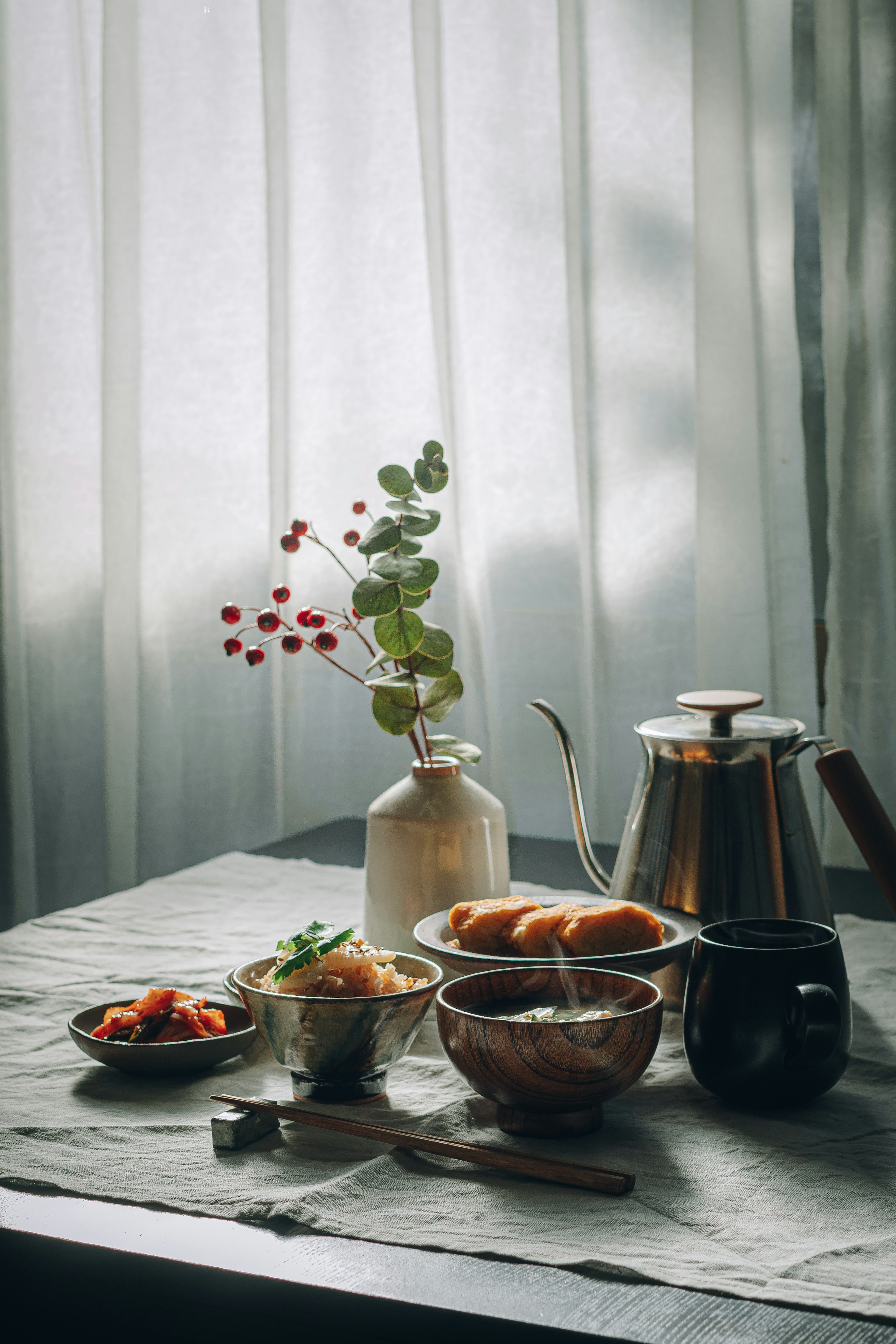 A serene breakfast table featuring coffee, croissants, and a vase with green leaves