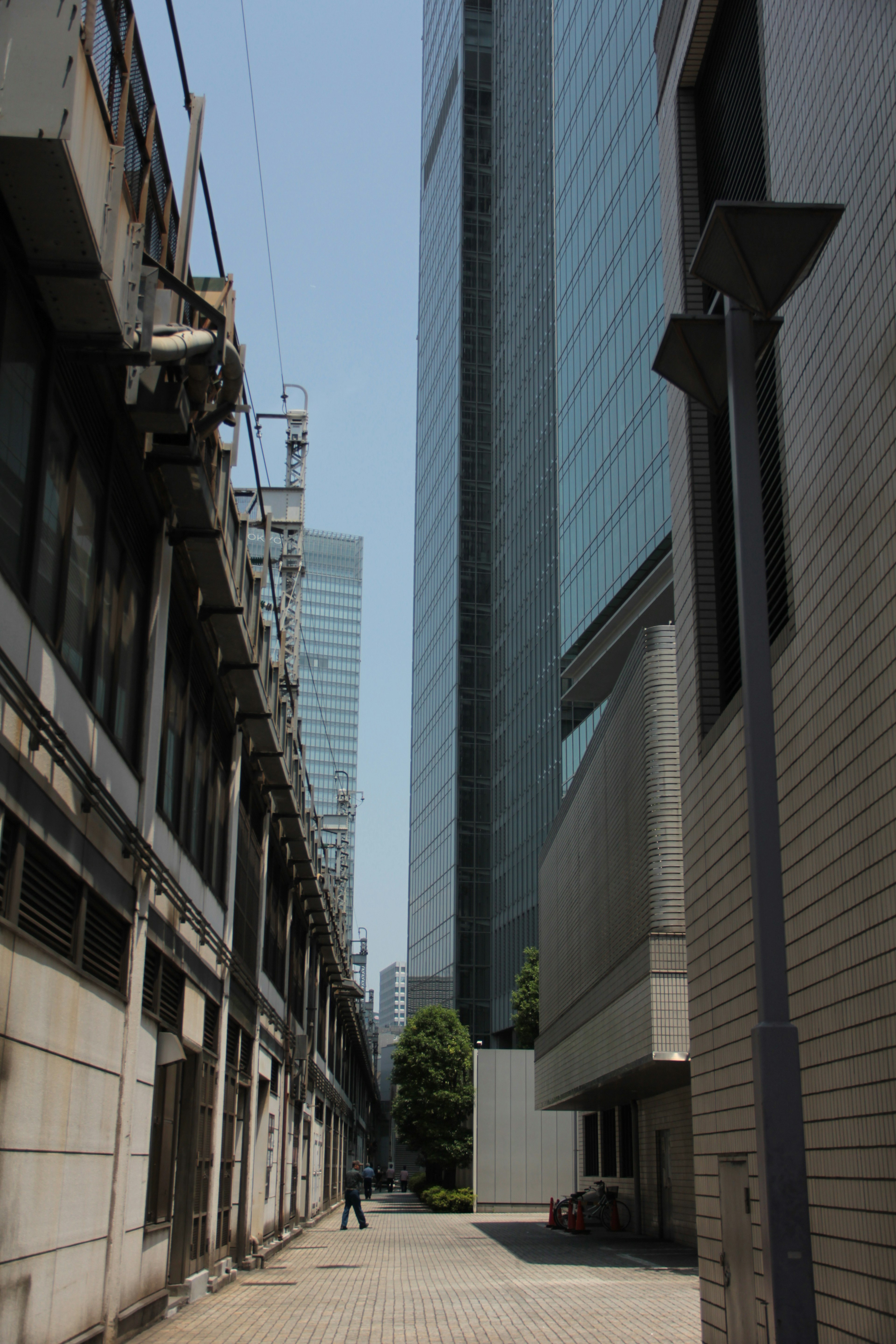 Jalan sempit dengan campuran gedung pencakar langit modern dan bangunan tua