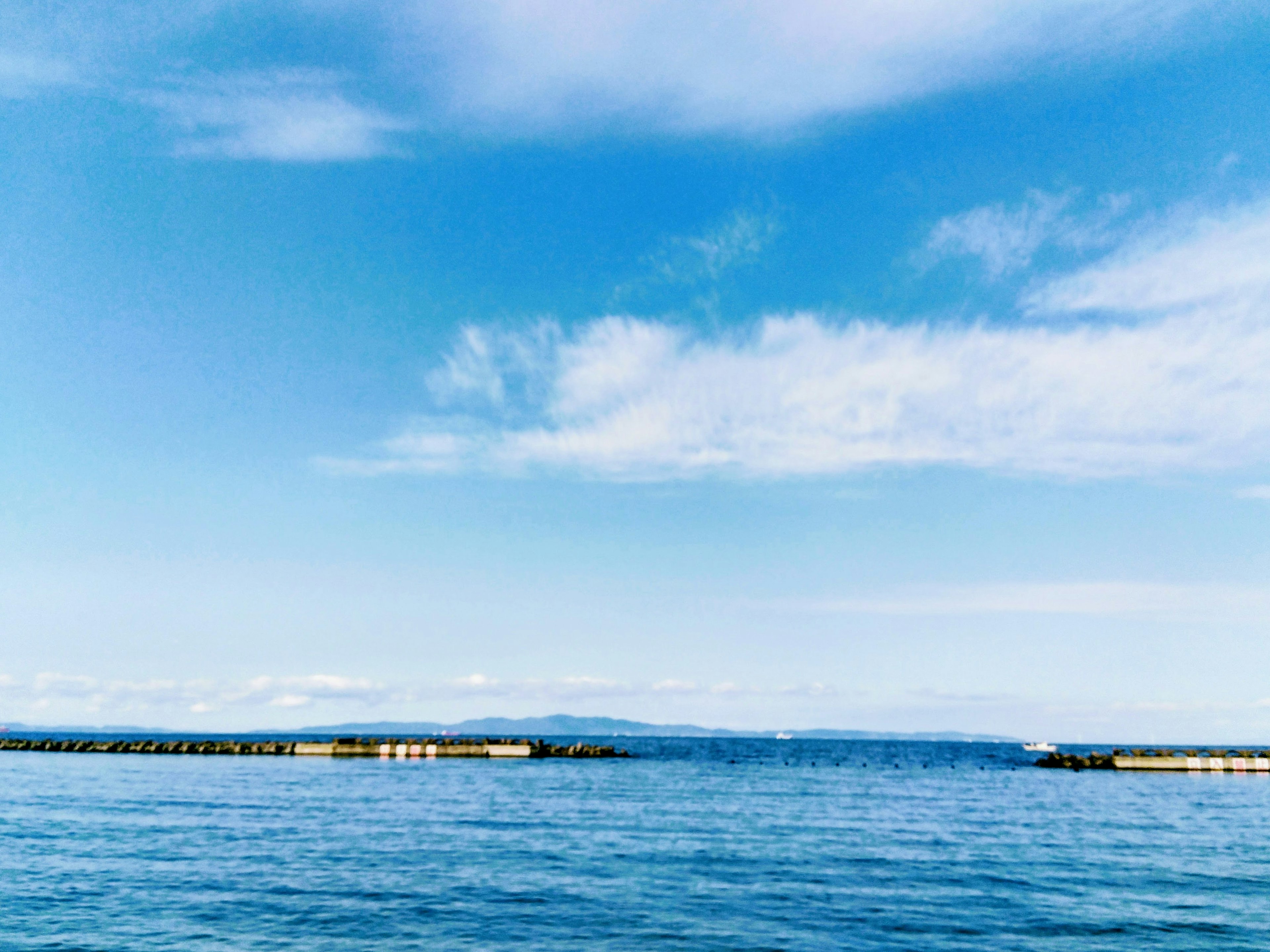 A scenic view of blue ocean and sky with a pier