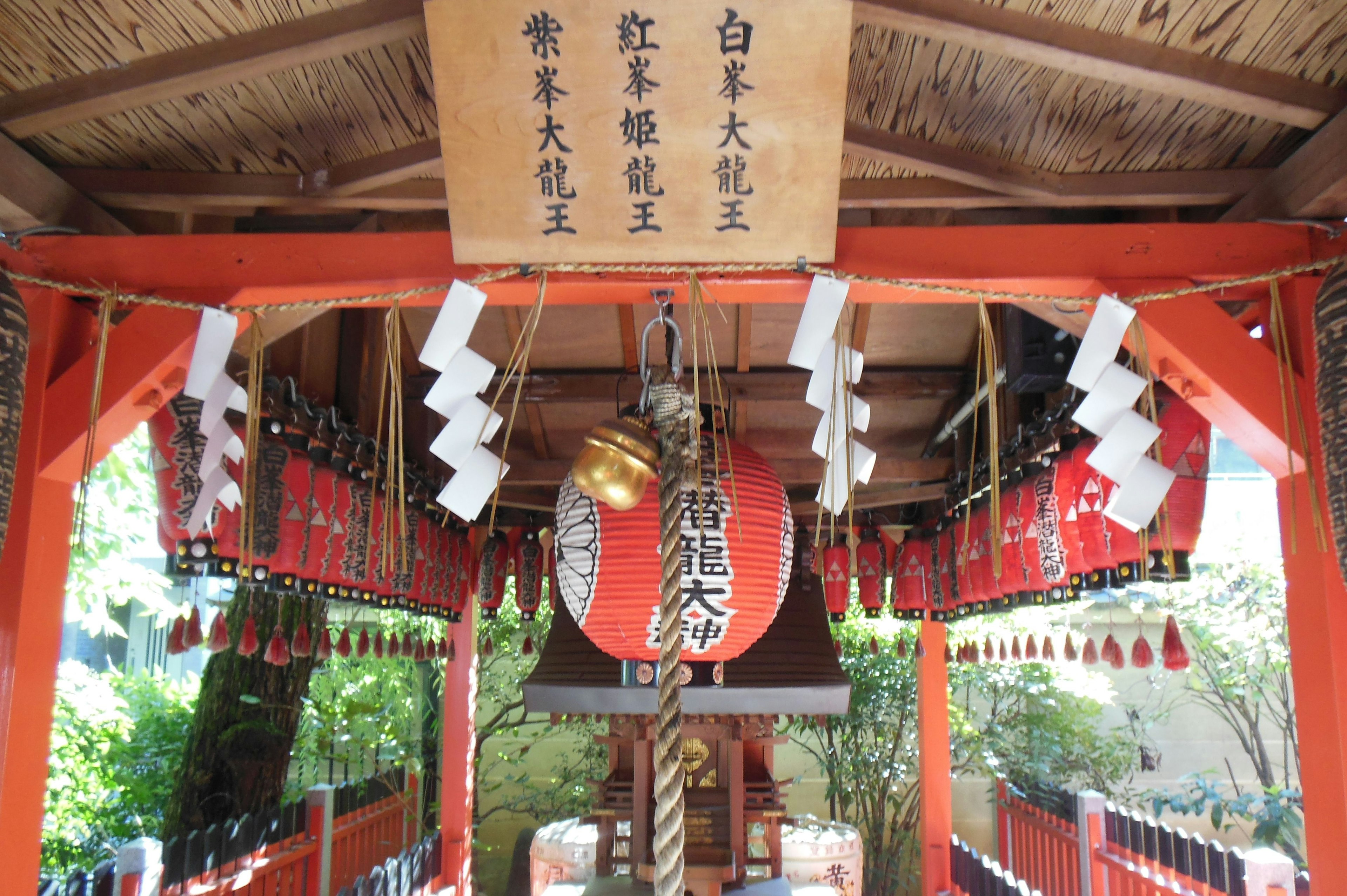 Interior of a shrine featuring a red torii gate and a bell altar