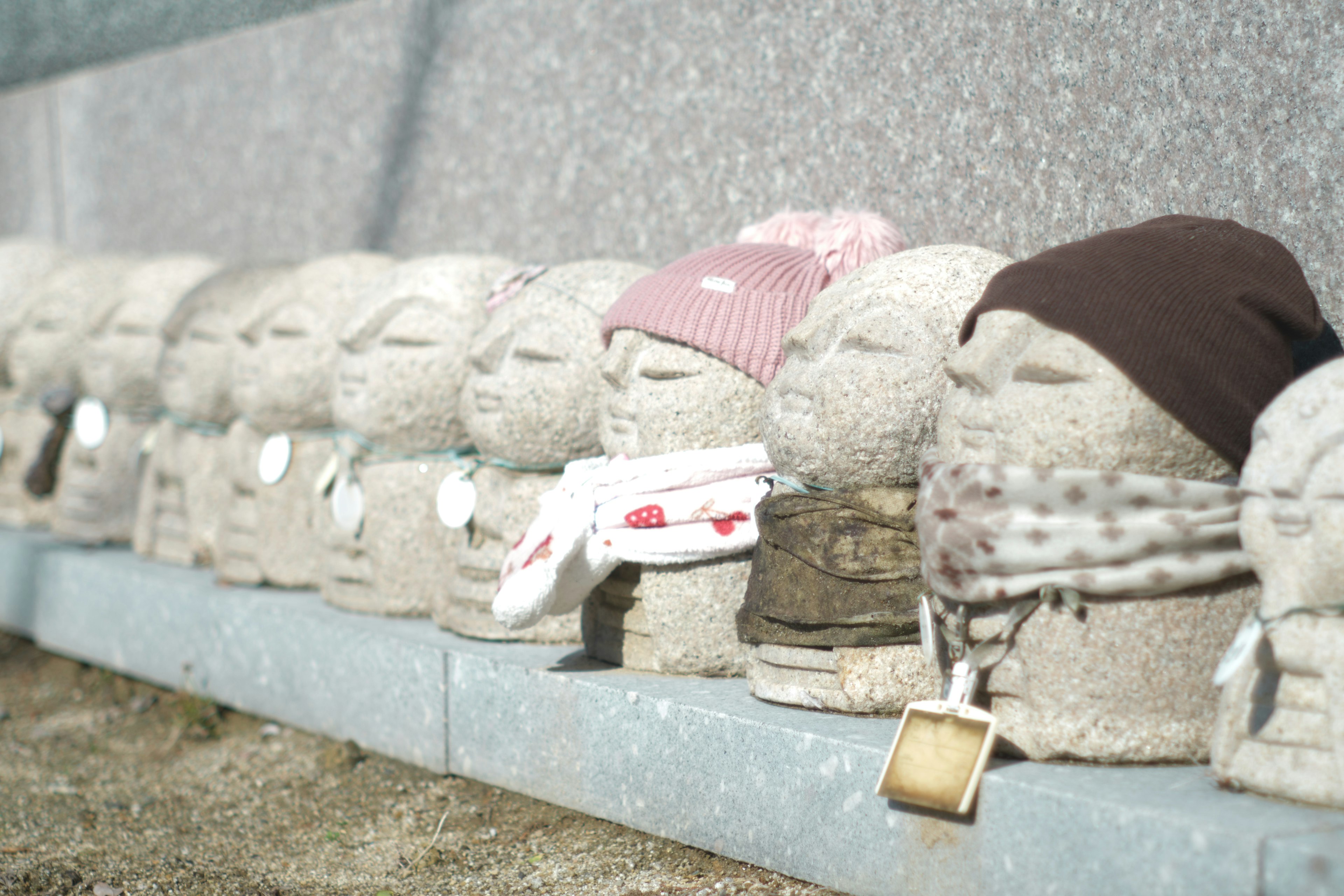 Row of stone figurines wearing various hats and clothing