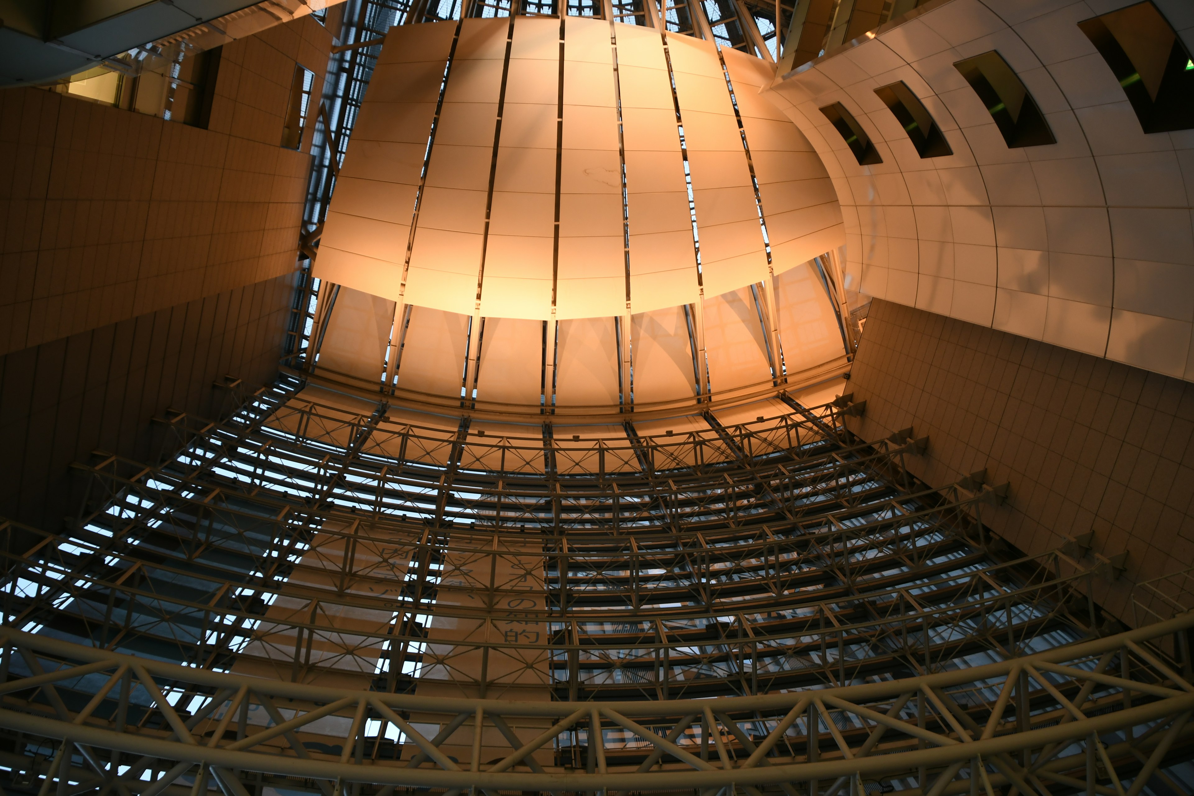 A photo looking up at the interior structure of a building with striking ceiling lighting