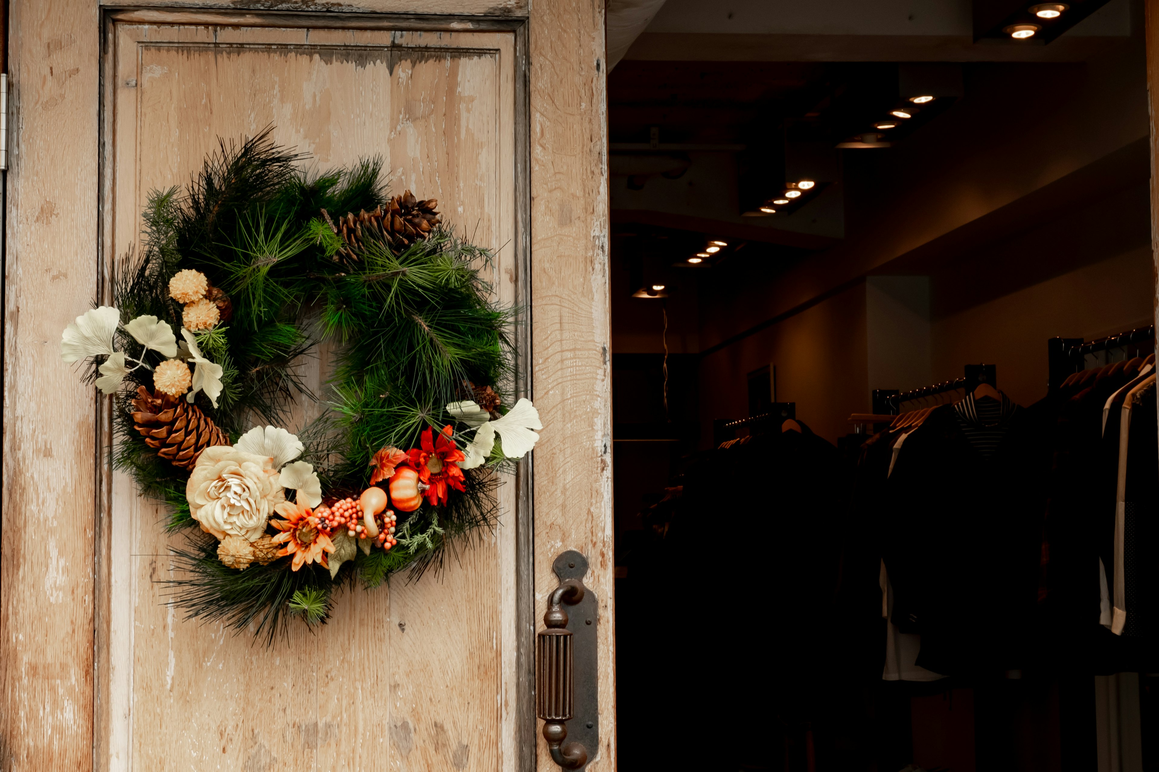 Couronne décorée de fleurs et de pommes de pin sur une porte en bois