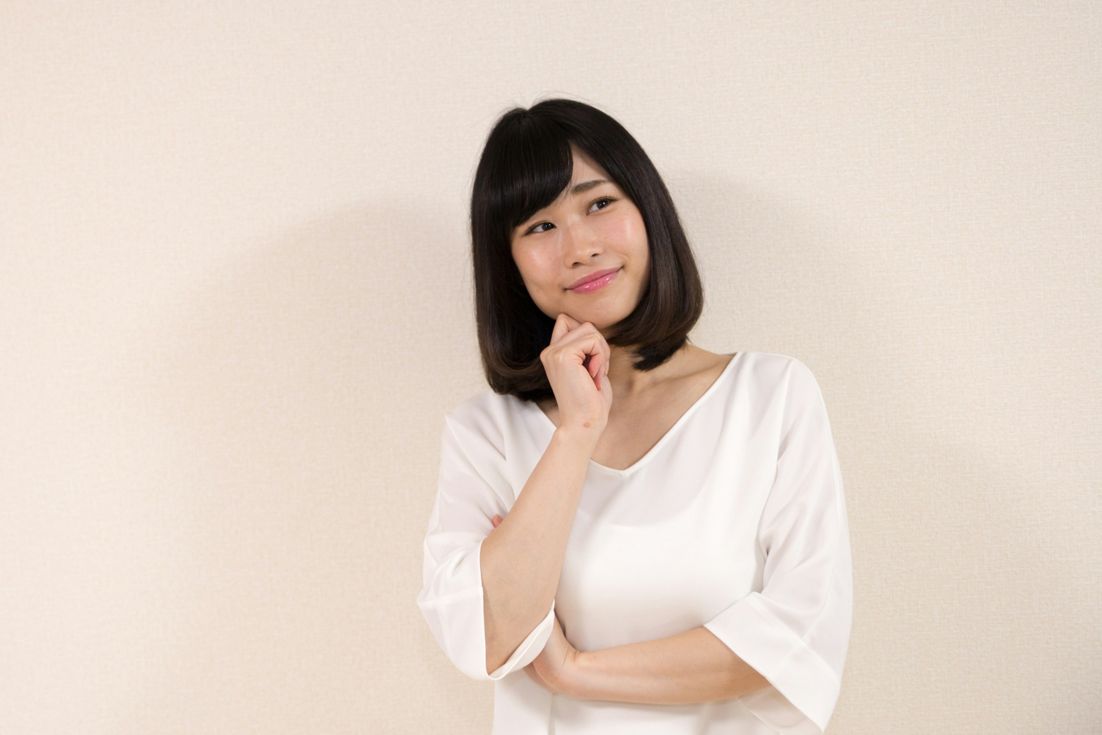 Woman in white clothing with a thoughtful expression