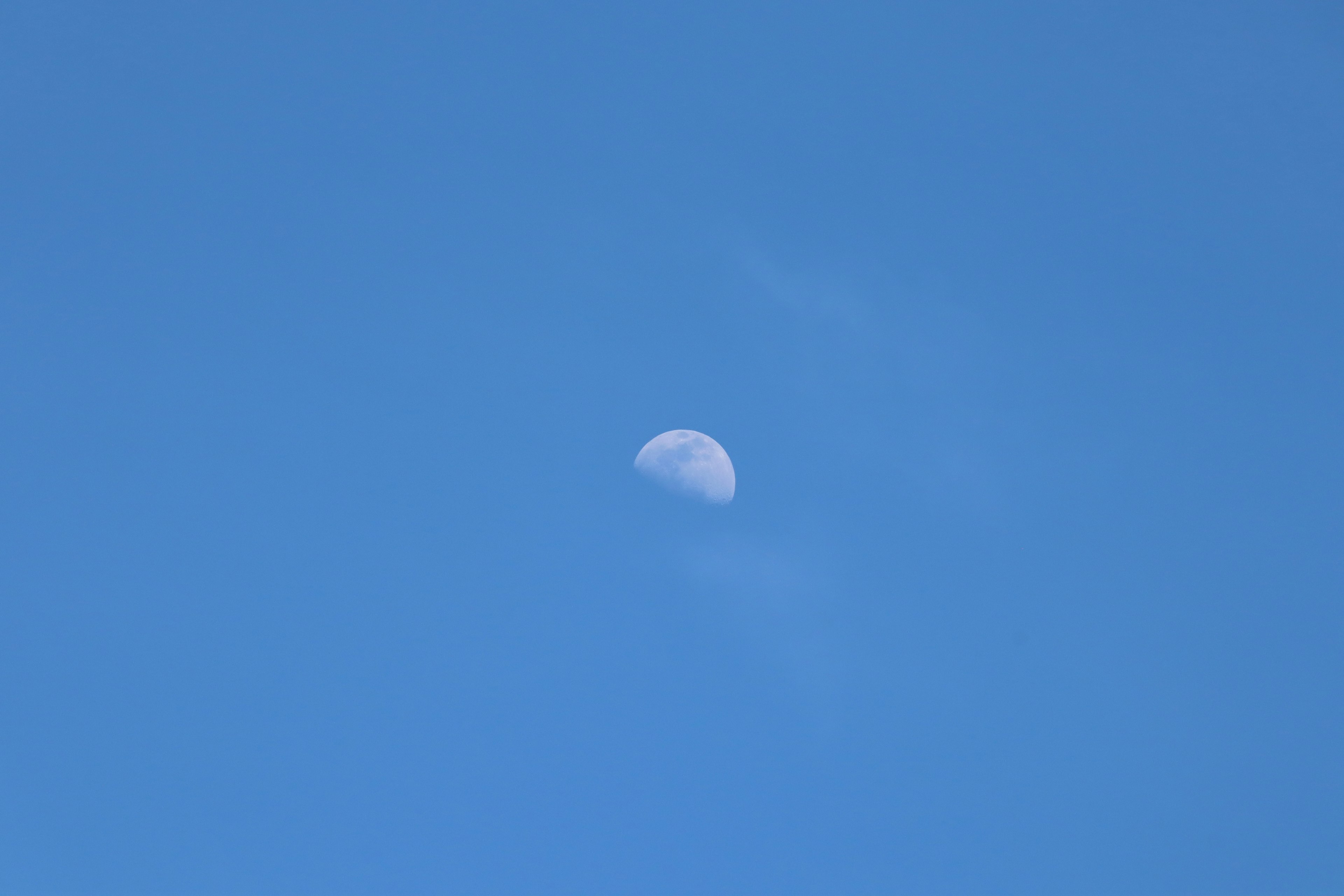 Bagian bulan terlihat di langit biru yang cerah