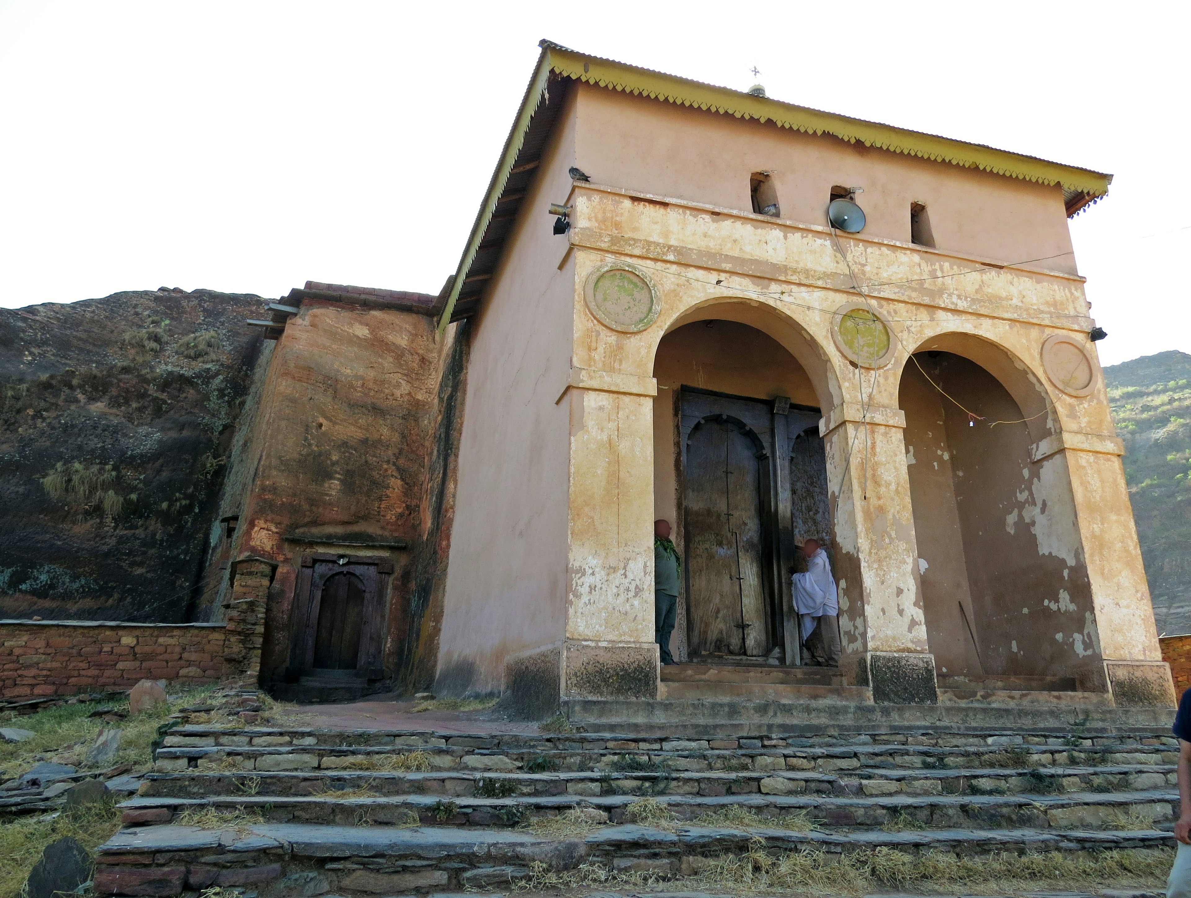 Ancient building featuring arched entrance surrounded by rocky hills