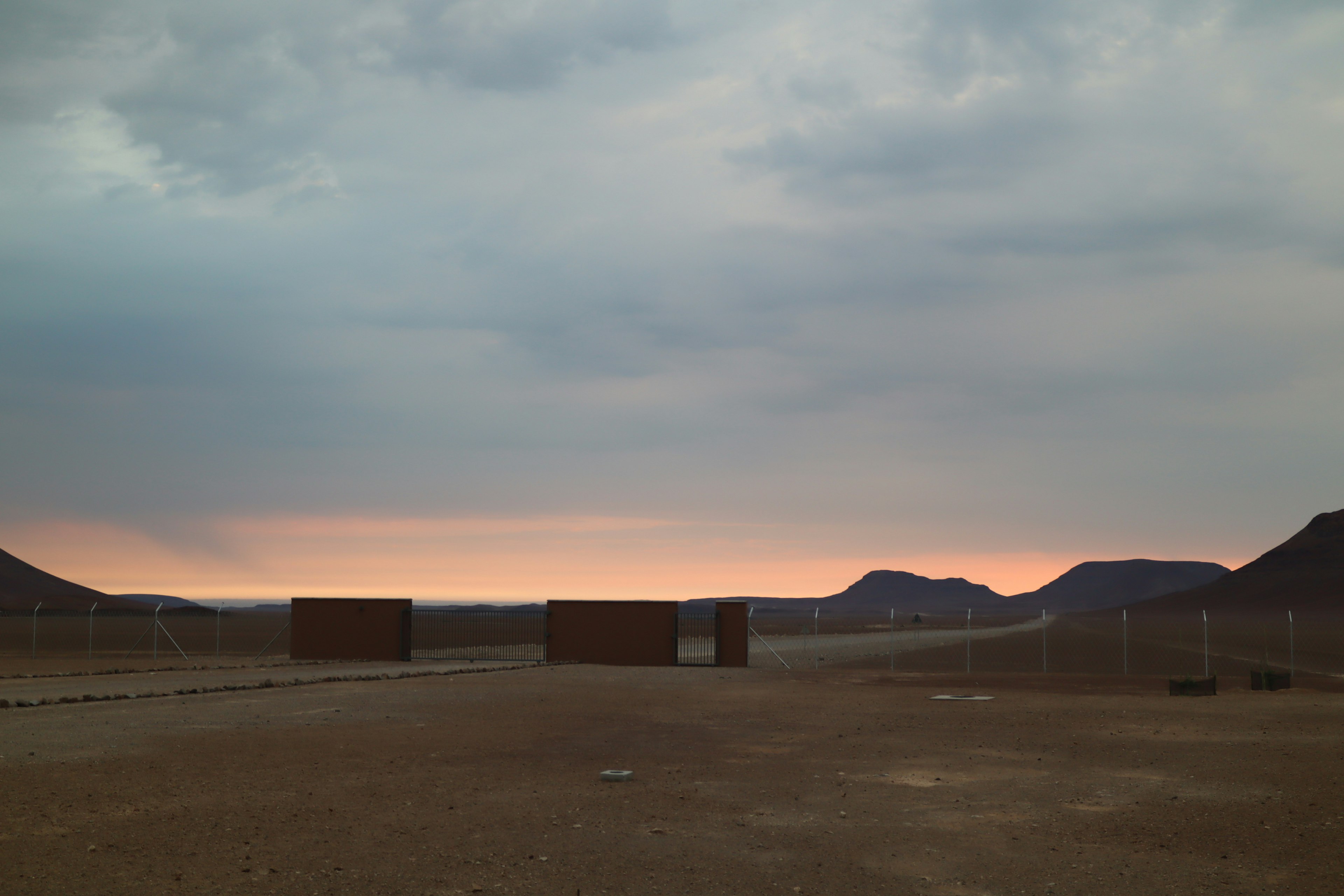 Container su un paesaggio vuoto con un cielo al tramonto e montagne sullo sfondo