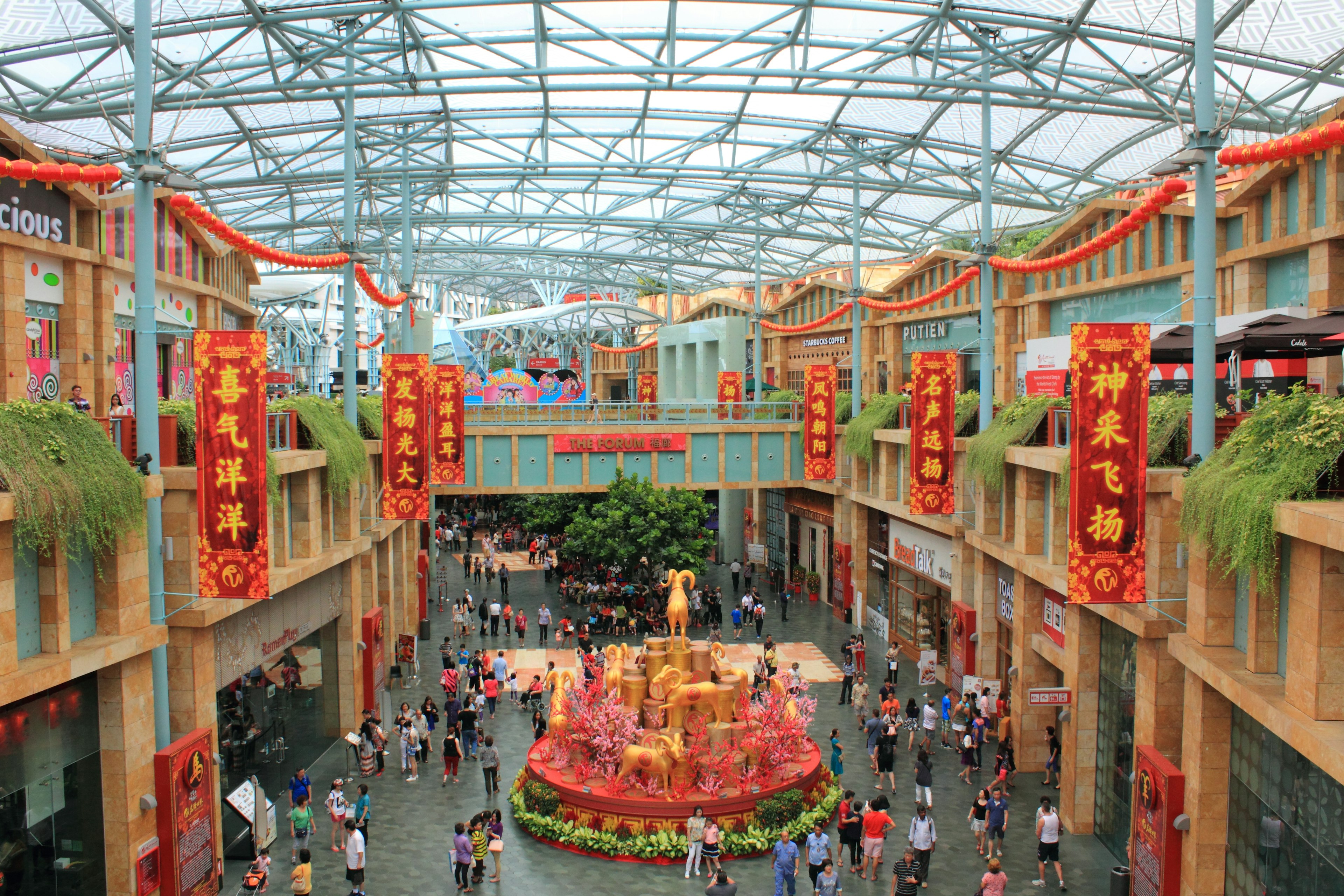 Vibrant interior of a shopping mall featuring a decorative fountain and crowds of people