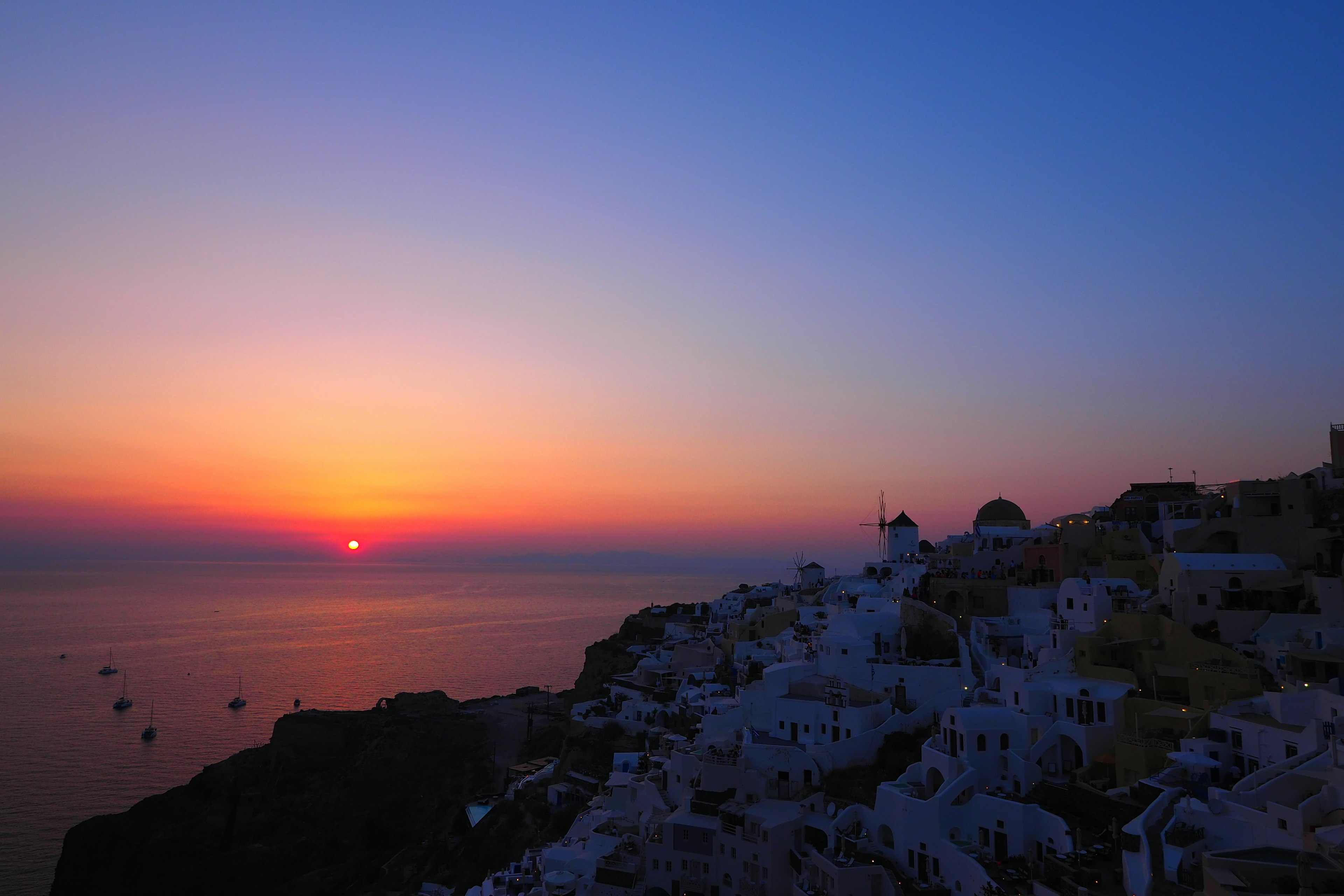 Stupendo tramonto sul mare con silhouette di edifici bianchi a Santorini