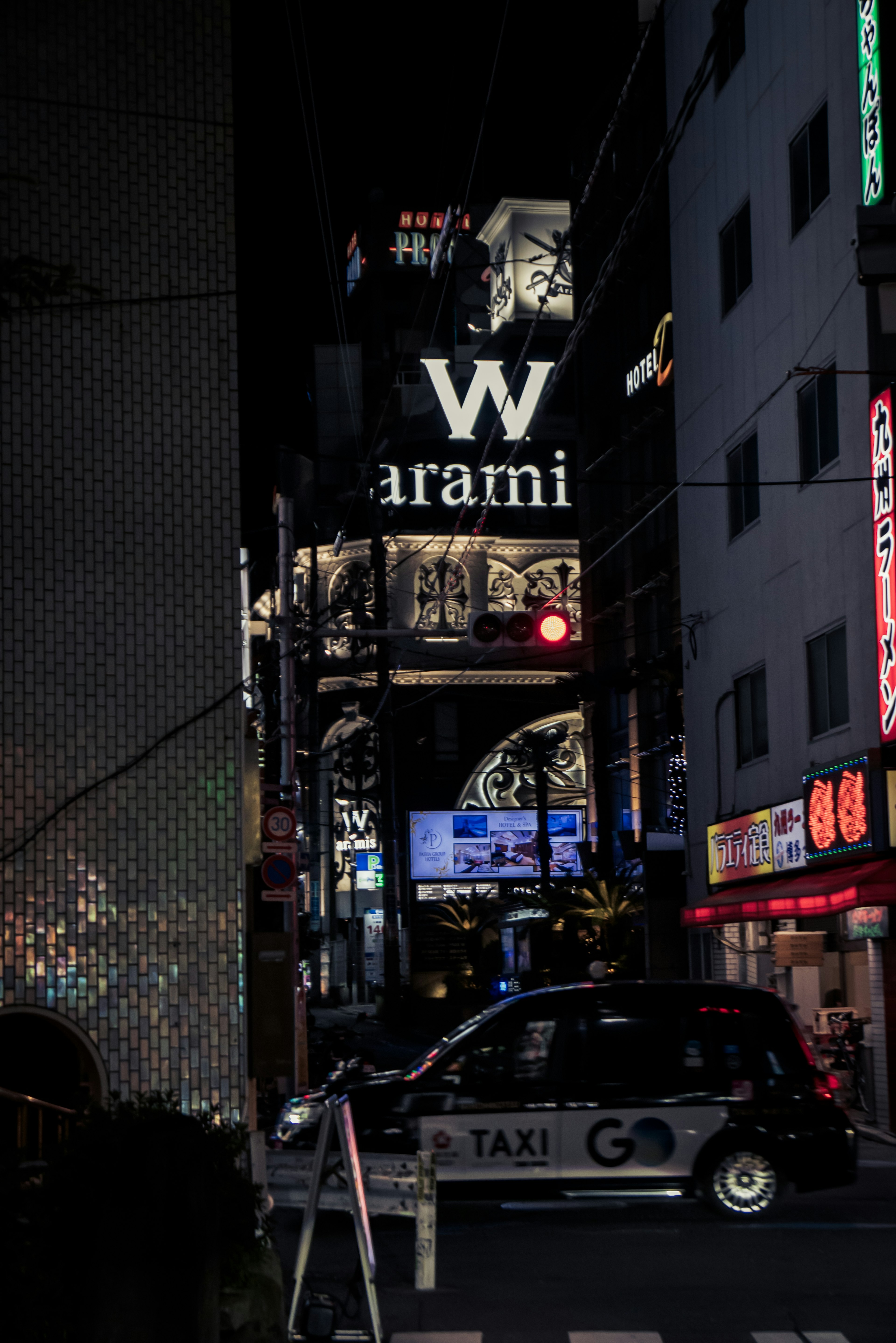 Night street scene featuring W logo and Arami sign