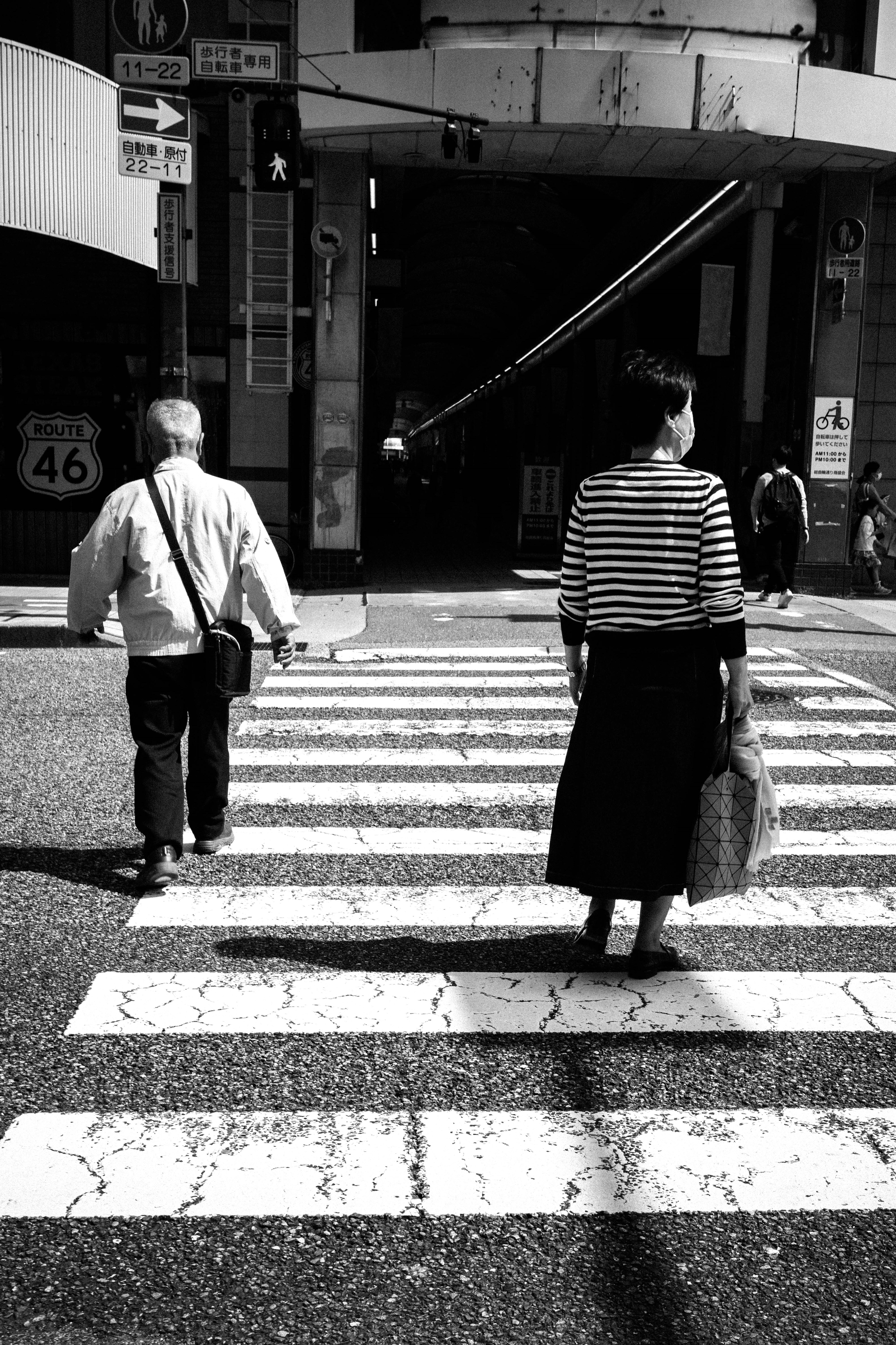 白黒の横断歩道を渡る二人の人物が写っている一枚