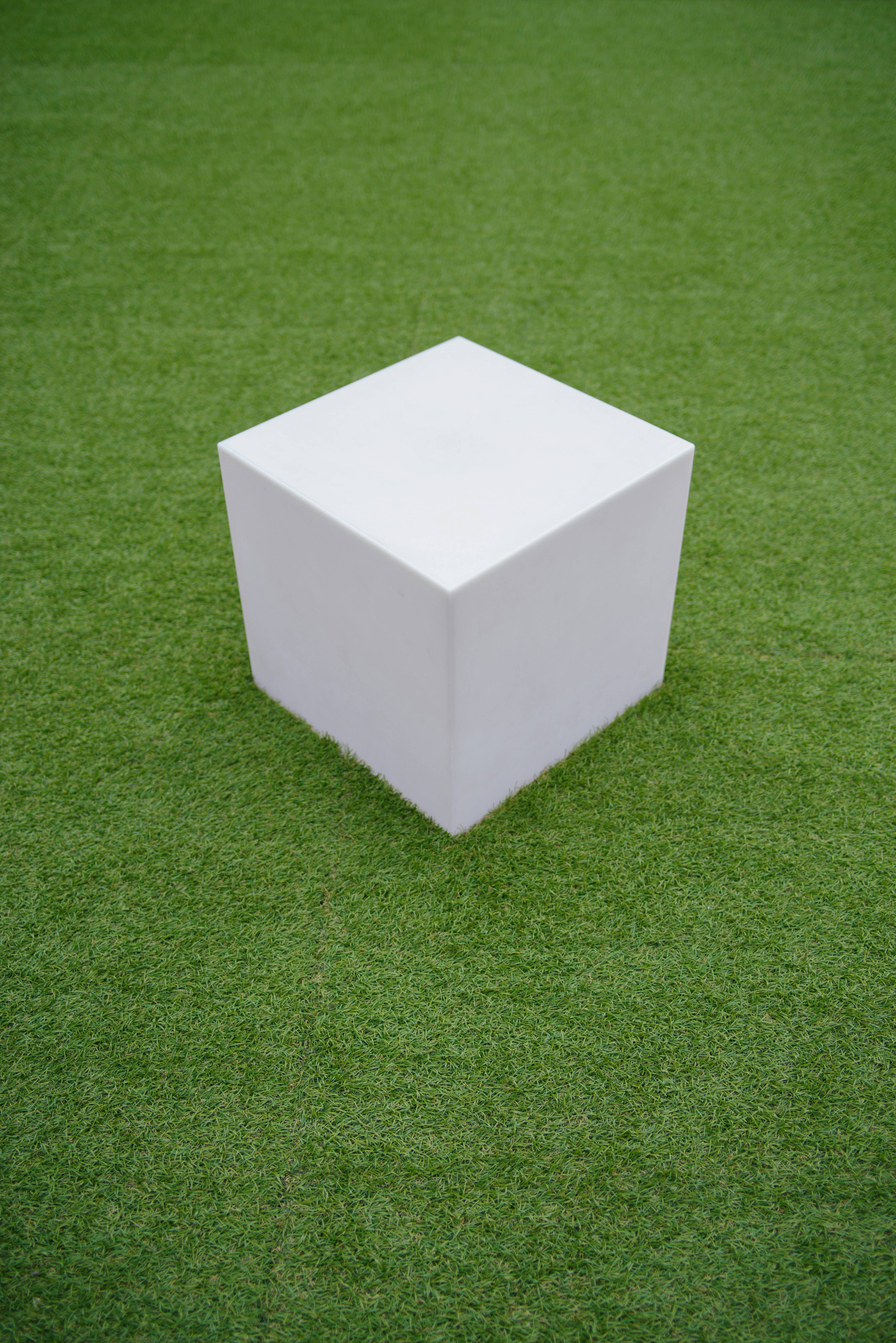 A white cube placed on green artificial grass