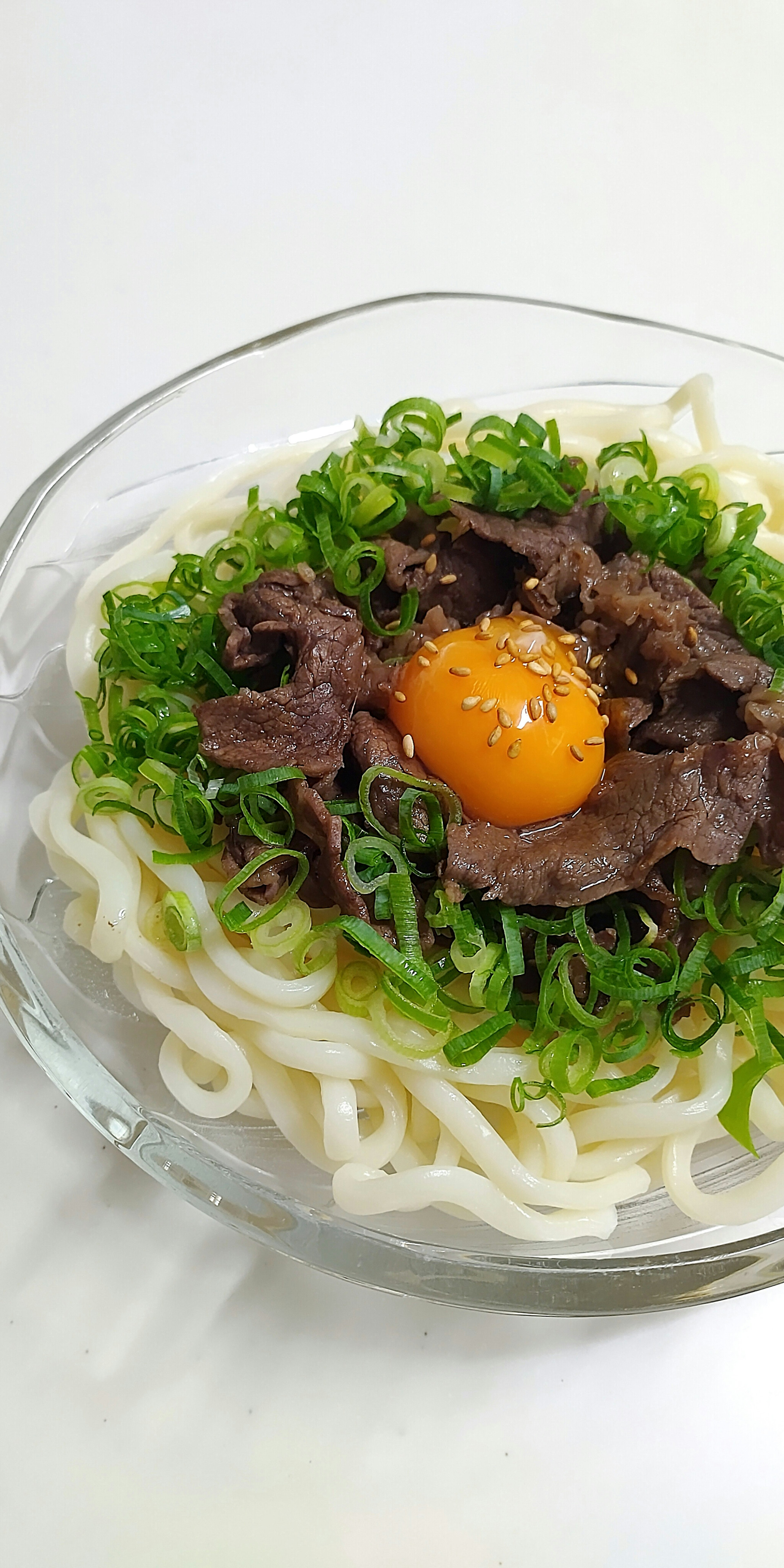 Dish of udon noodles topped with beef and egg yolk