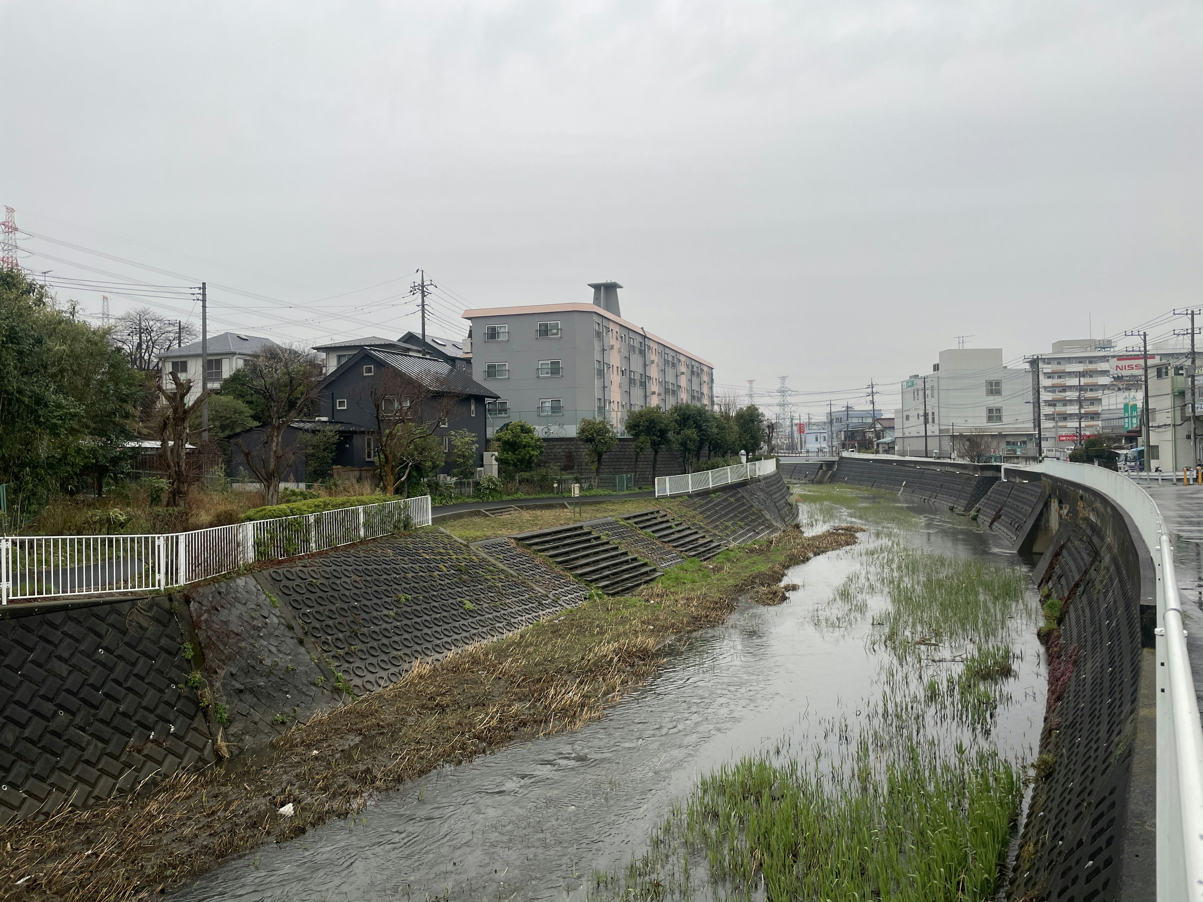 Landscape featuring buildings and grass along a riverbank