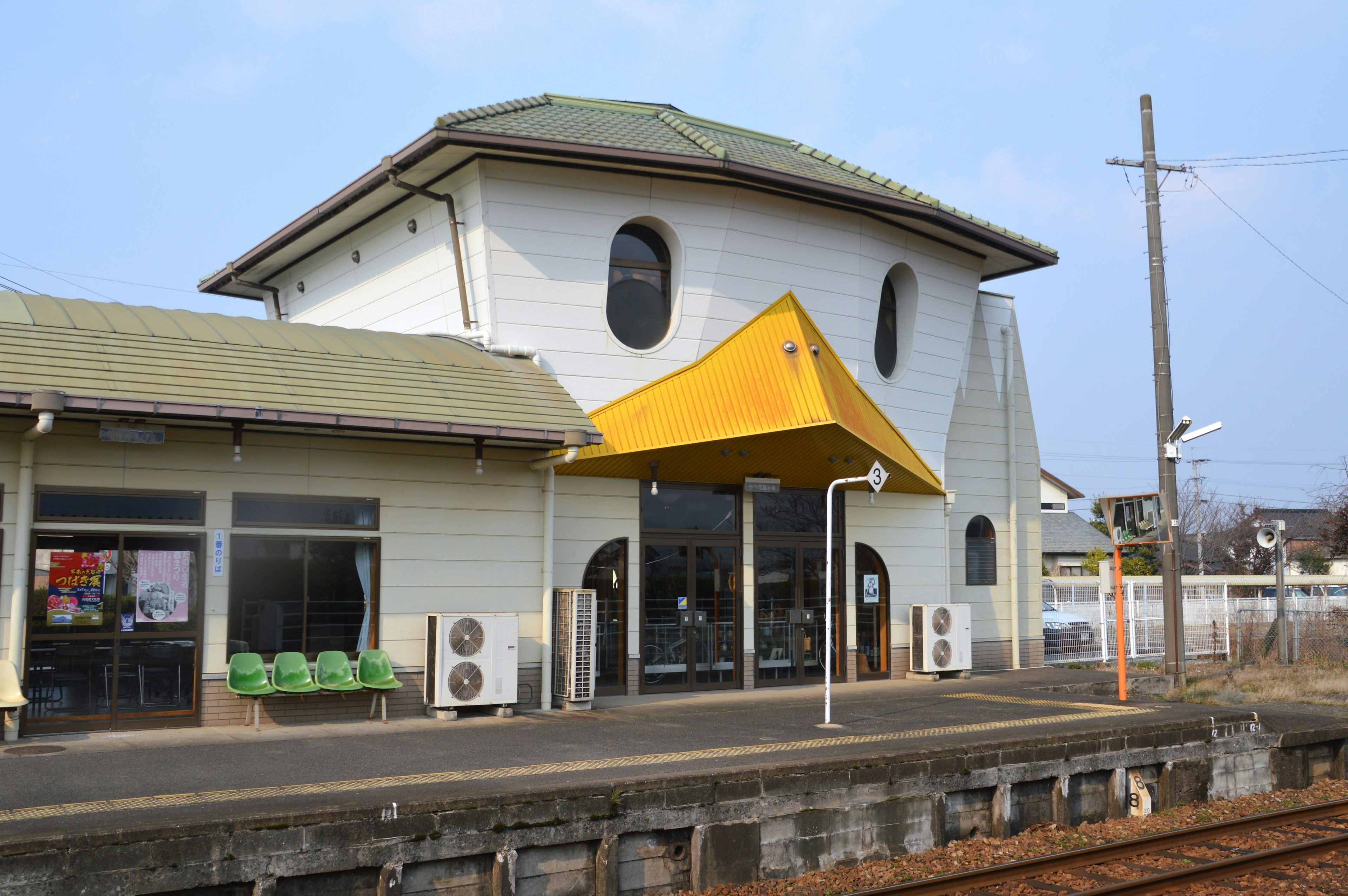 Edificio della stazione ferroviaria a forma di uccello con tetto verde e awning giallo