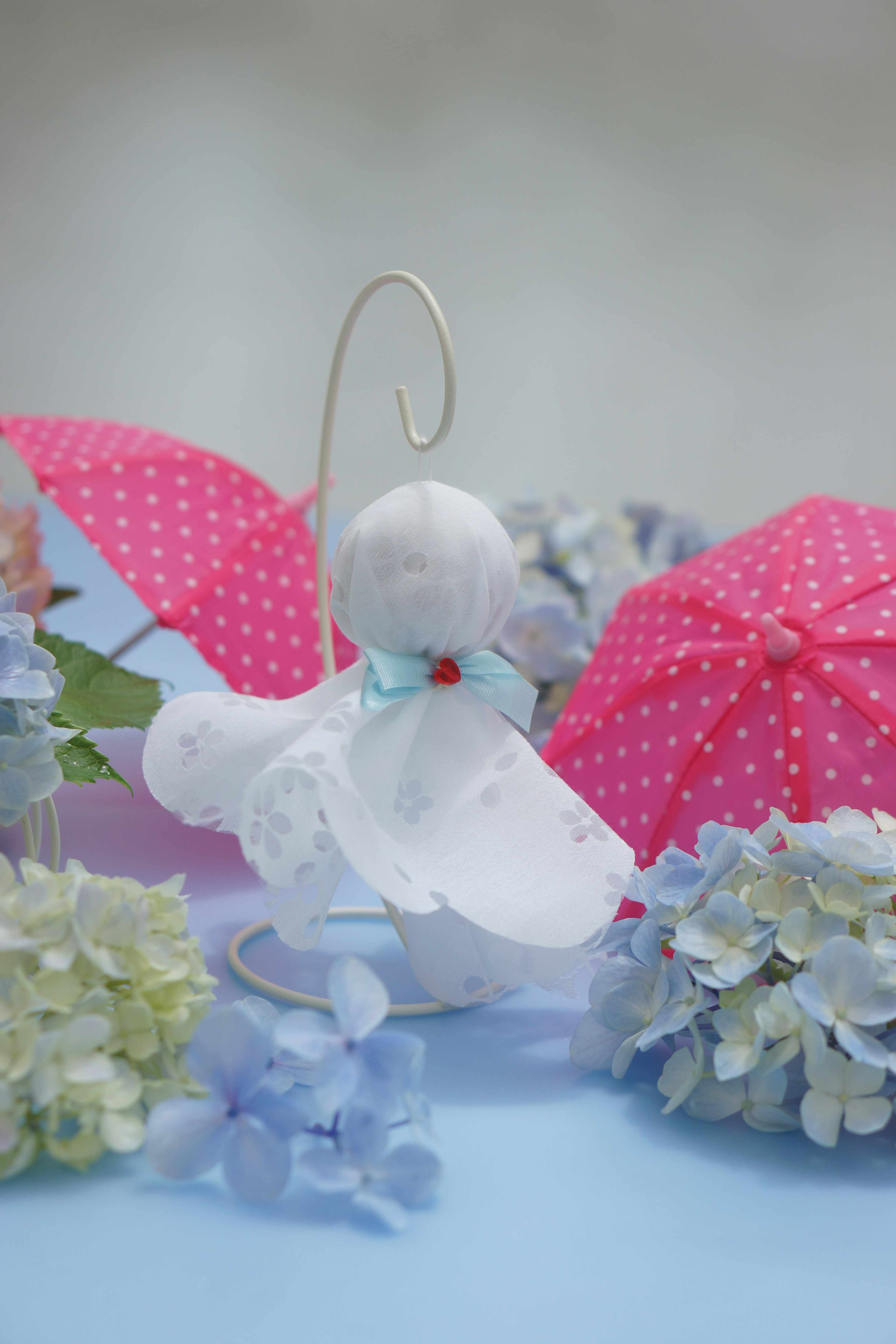 Cute scene with a doll in a white dress and pink polka dot umbrellas